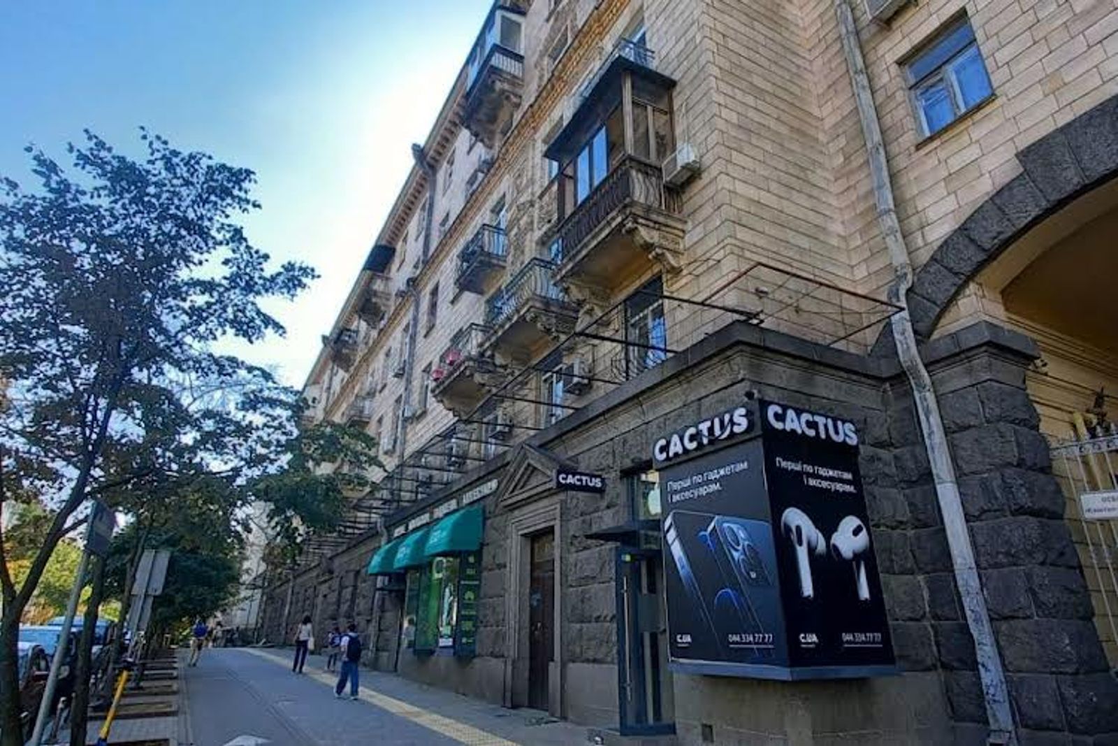 Building facade with balconies and storefronts under blue sky, Kyiv — Vestor.Estate