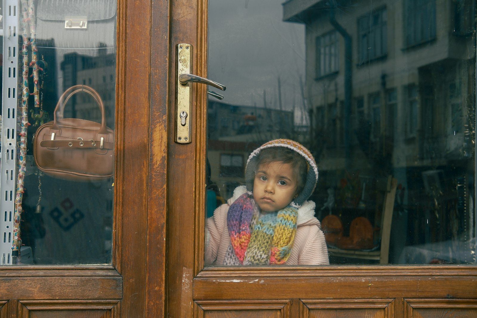 A young child looking thoughtfully out of a window