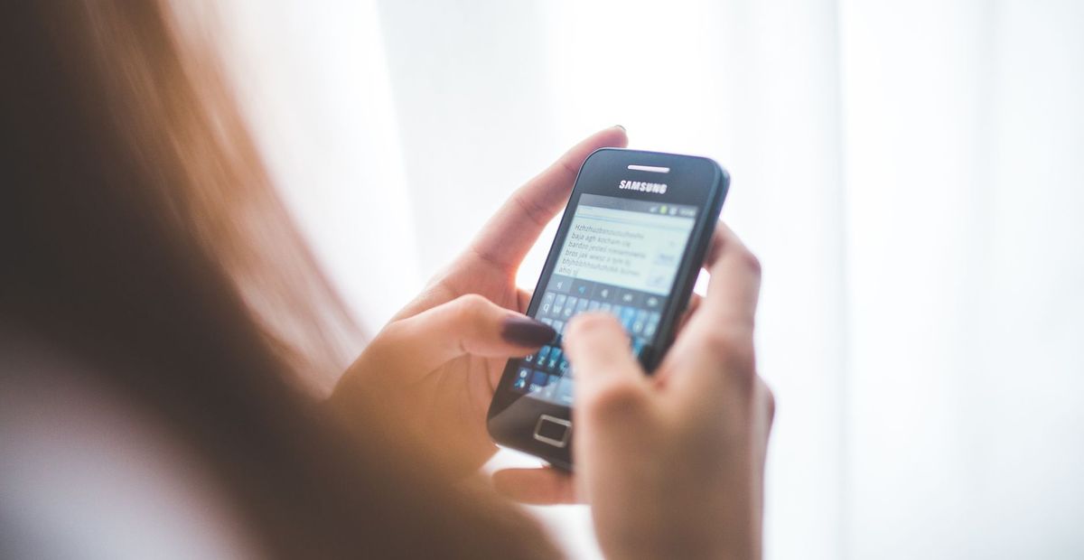 A hand holding a smartphone with a messaging conversation open