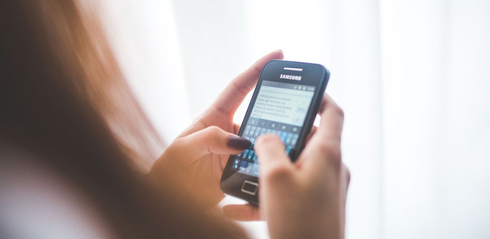 A hand holding a smartphone with a messaging conversation open