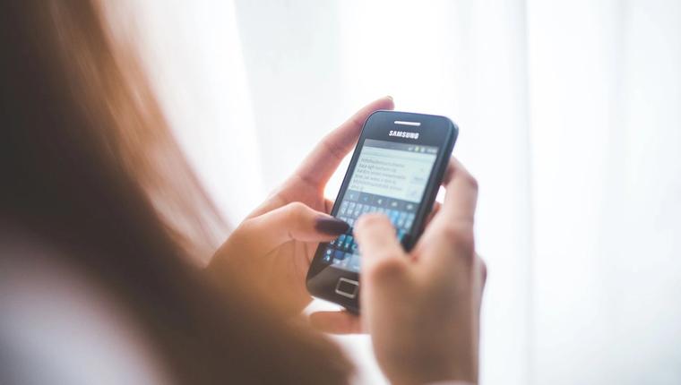 A hand holding a smartphone with a messaging conversation open