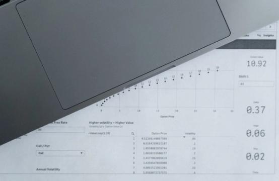 Nešiojamasis kompiuteris ir atspausdintos duomenų lentelės ant darbo stalo. Asociatyvi nuotrauka.