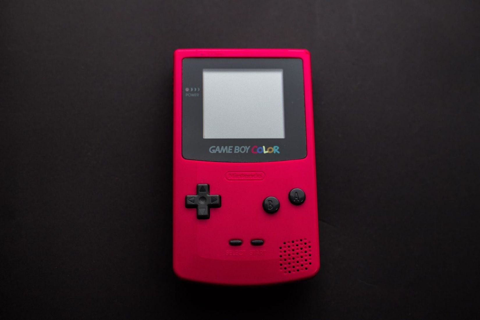 Close-up of a red Nintendo Game Boy Color on a dark backdrop