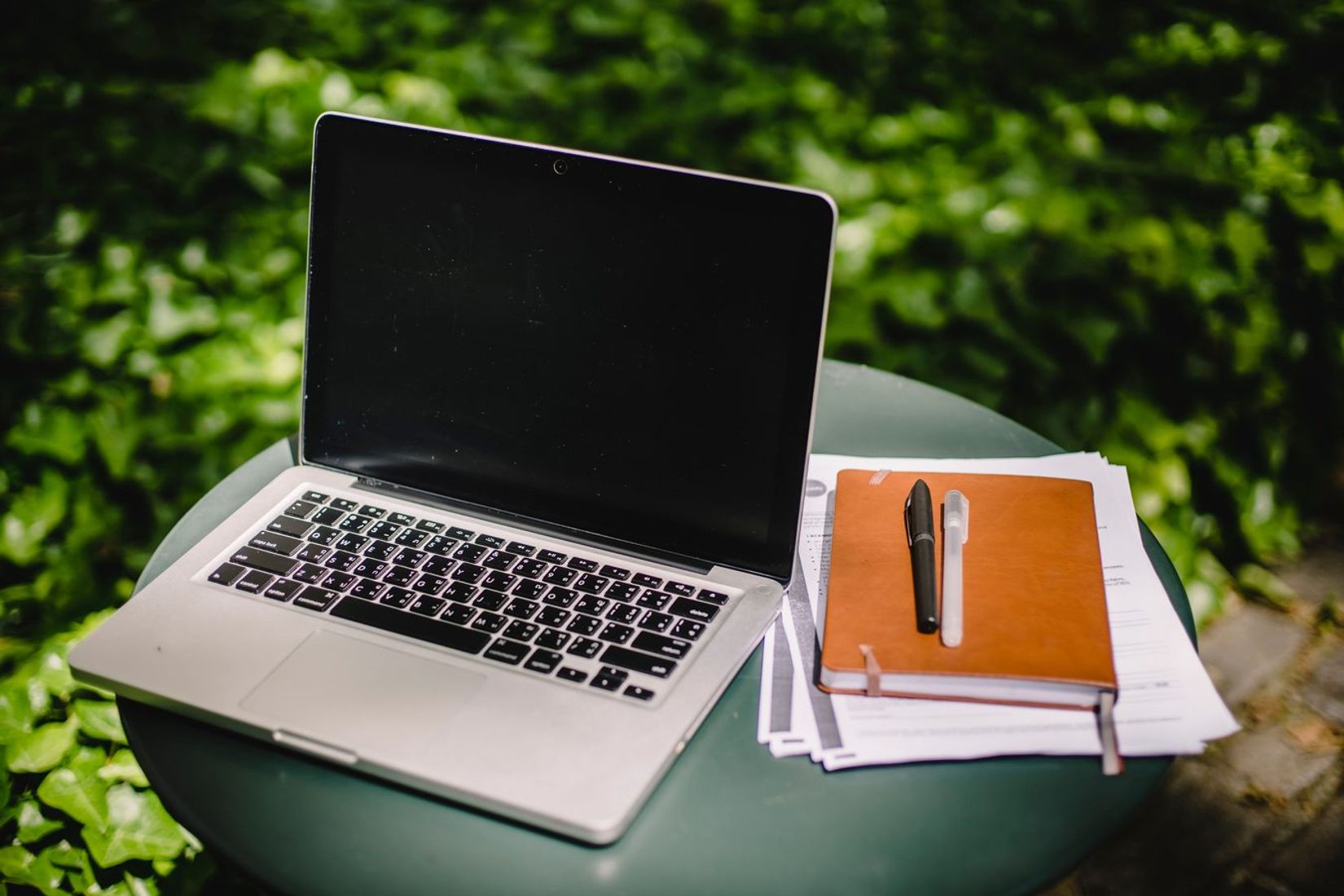 Modern netbook beside a notebook and papers, symbolizing shared notes and collaboration