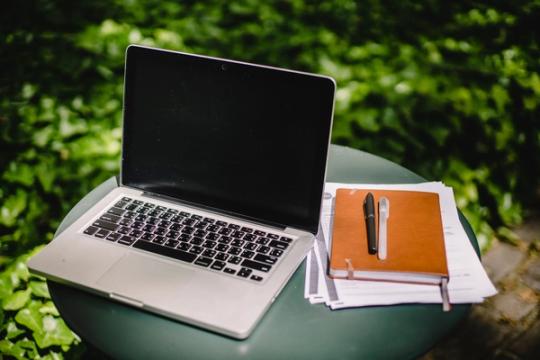 Modern netbook beside a notebook and papers, symbolizing shared notes and collaboration