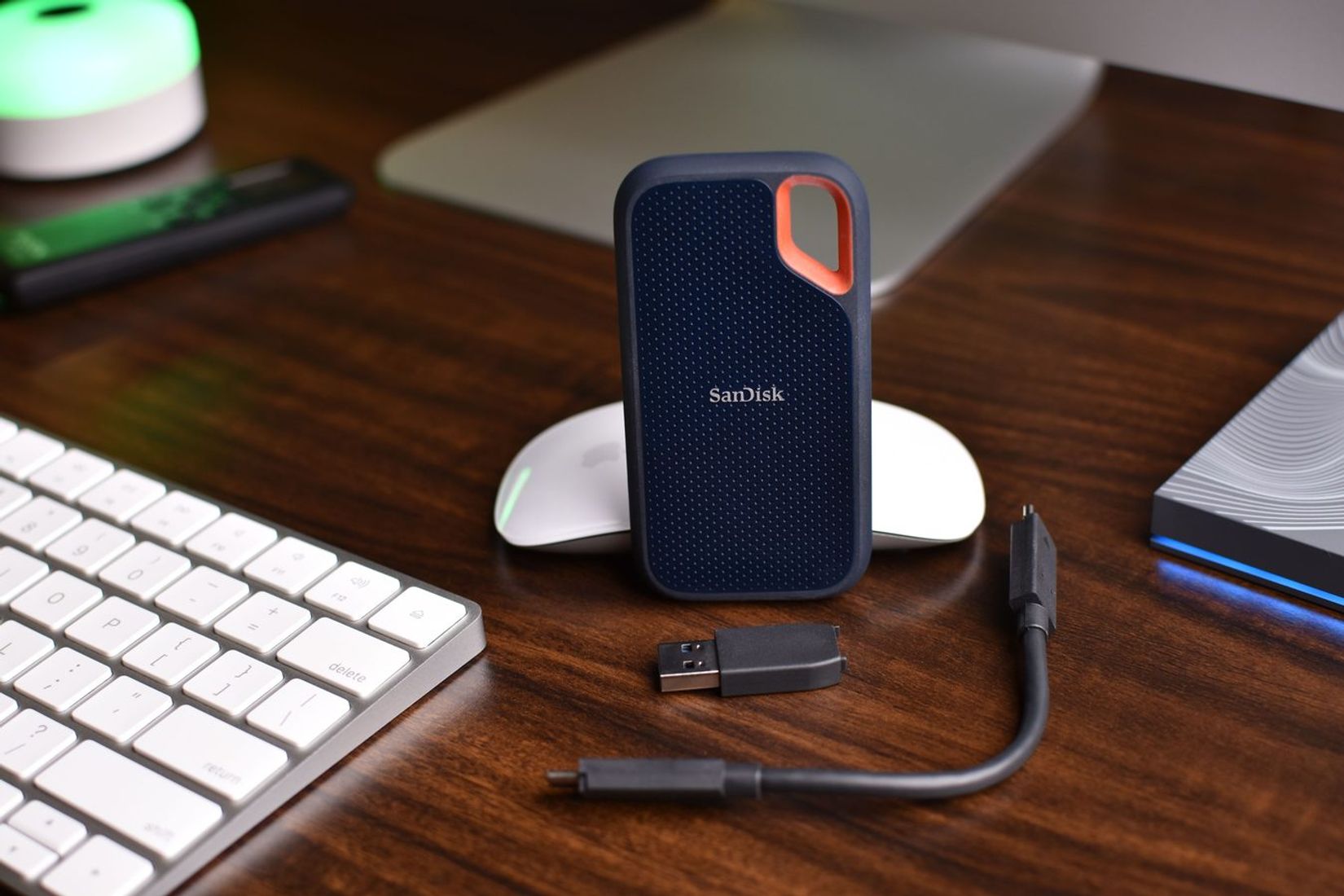 Portable SSD su kabeliu ant medinio stalo.