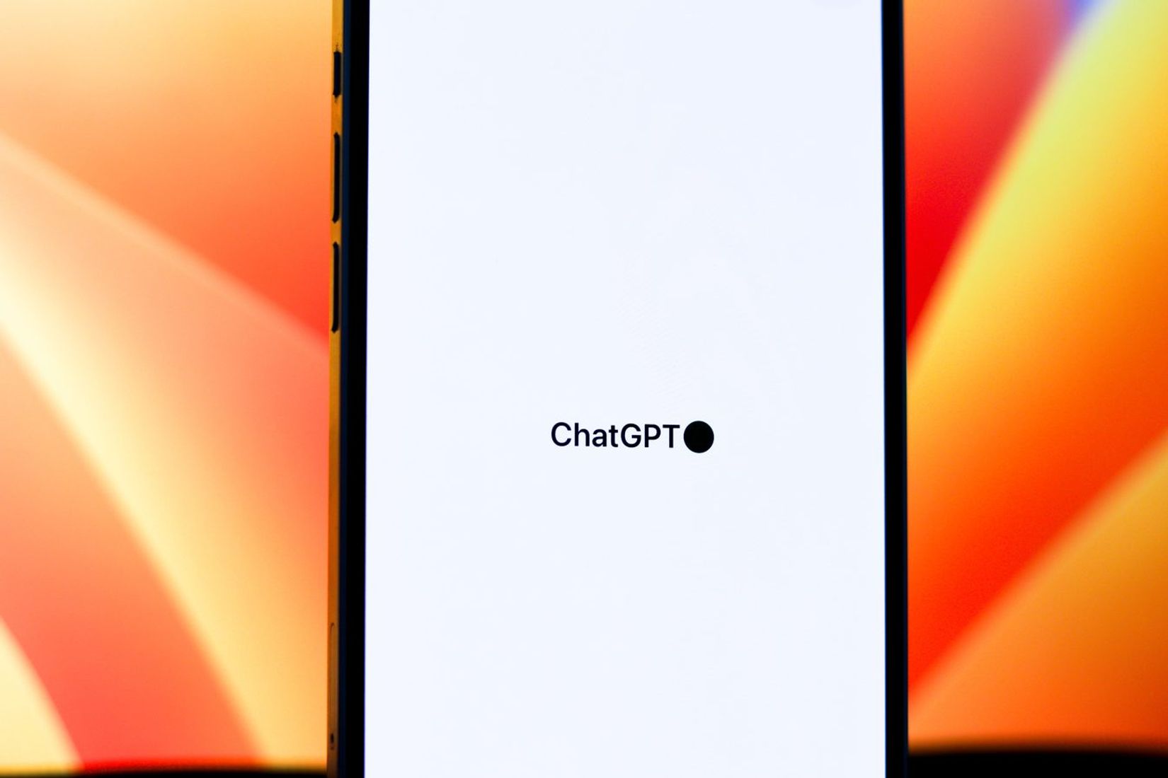 Išmanusis telefonas su atidaryta ChatGPT programėle spalvingame fone