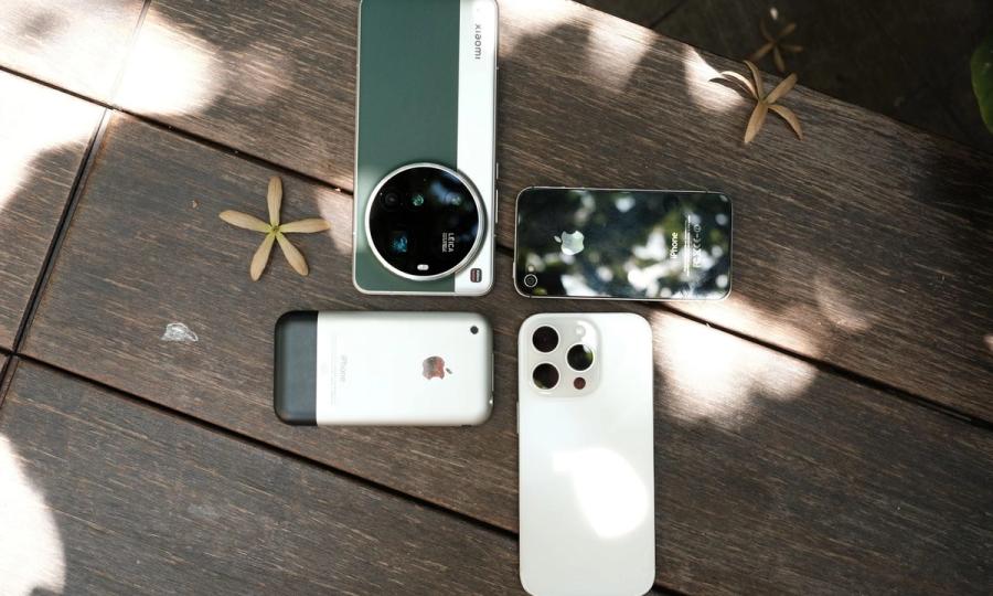 Trys šiuolaikiniai išmanieji telefonai ant medinio stalo.