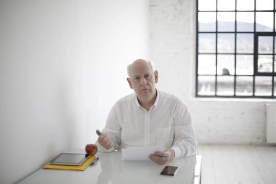 Senior male executive in formal wear sitting at table and signing papers during working day in modern workspace at daytime