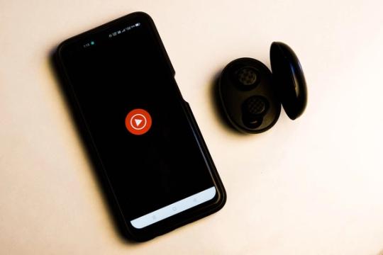 Išmanusis telefonas ir belaidės ausinės ant stalo