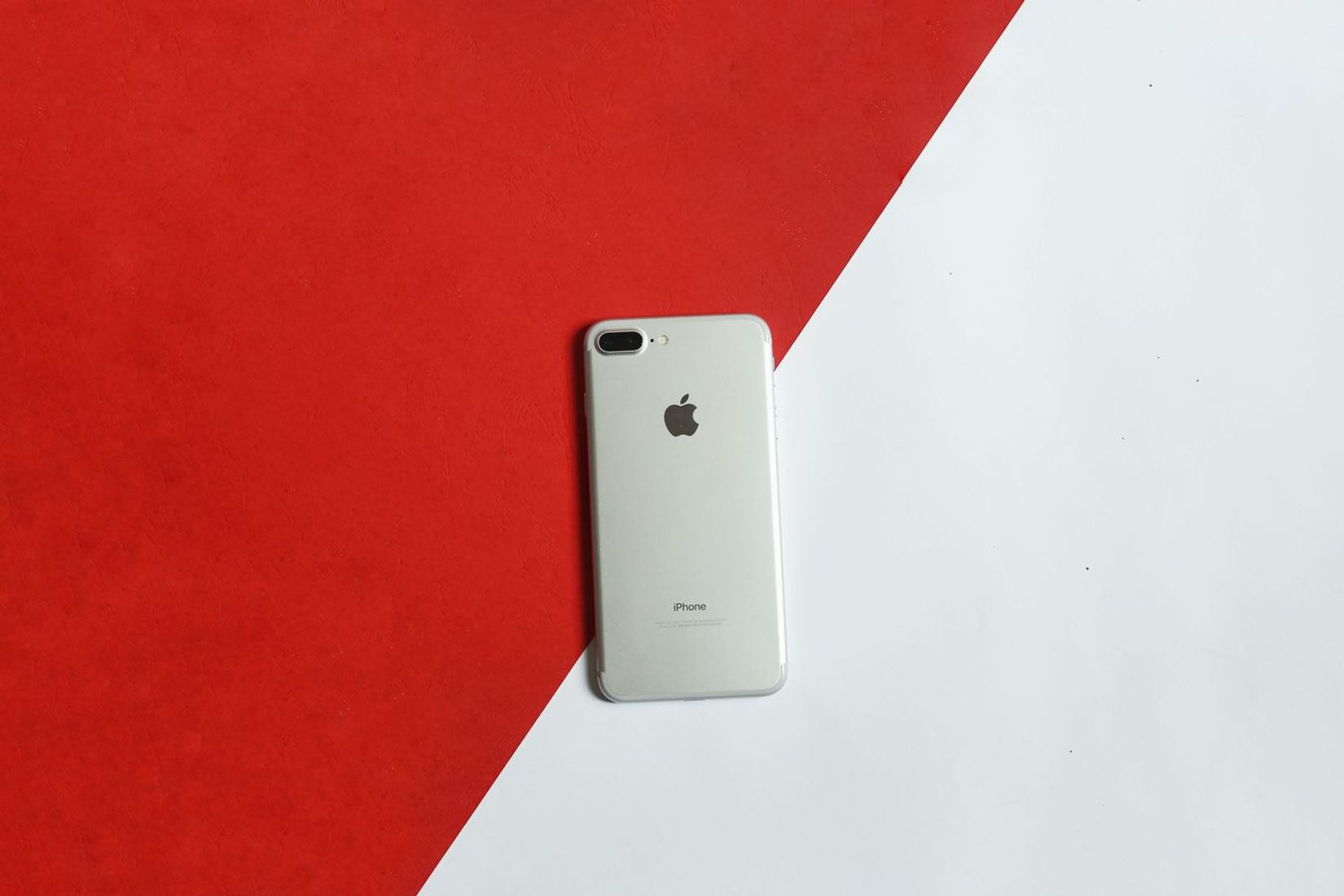 A silver smartphone placed on a contrasting red and white background captured from above.
