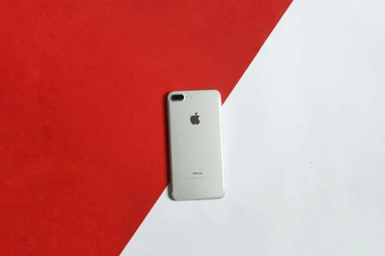 A silver smartphone placed on a contrasting red and white background captured from above.