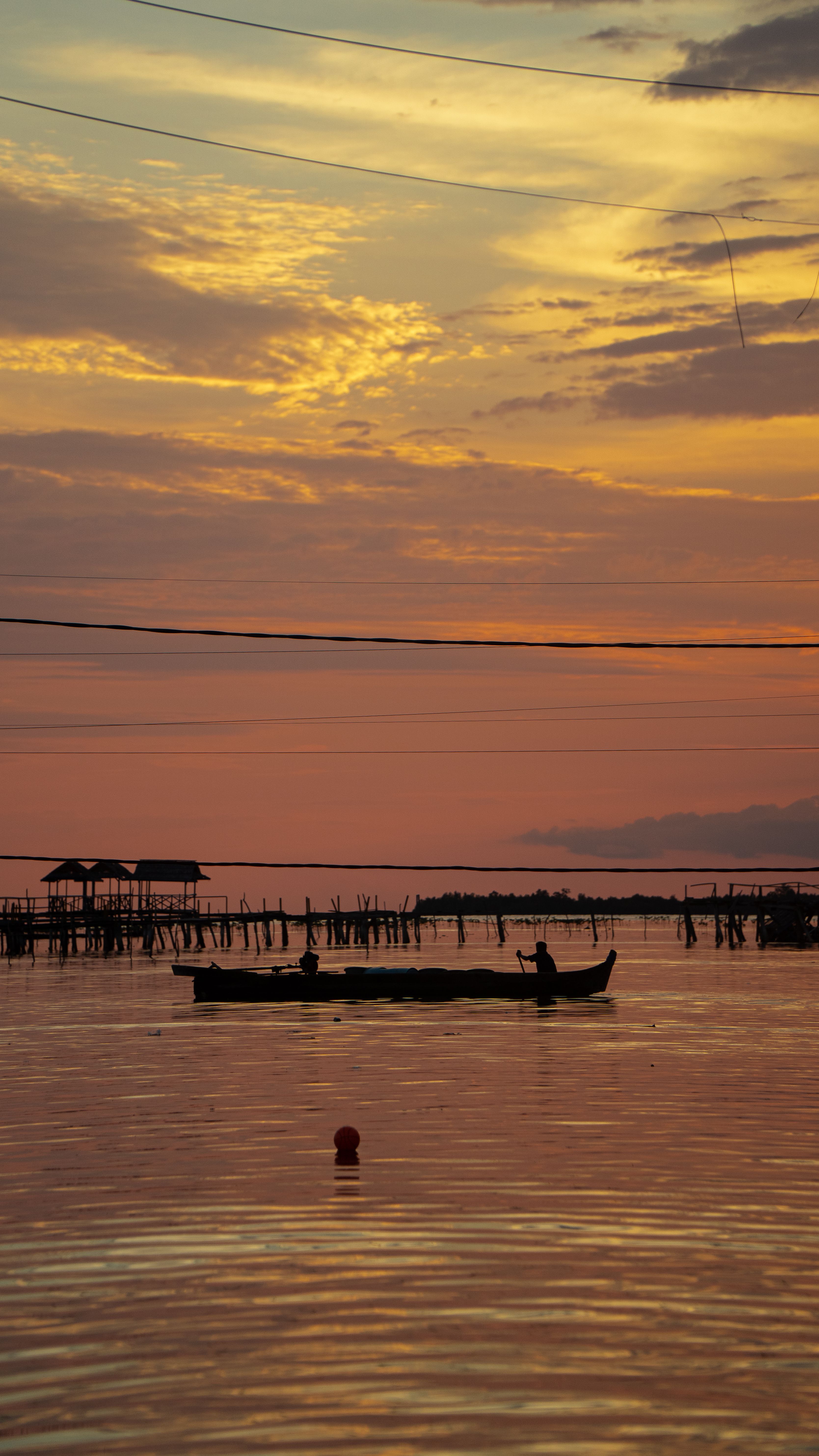 Two fishermen paddling a traditional boat at dusk on the coastal waters of Torosiaje