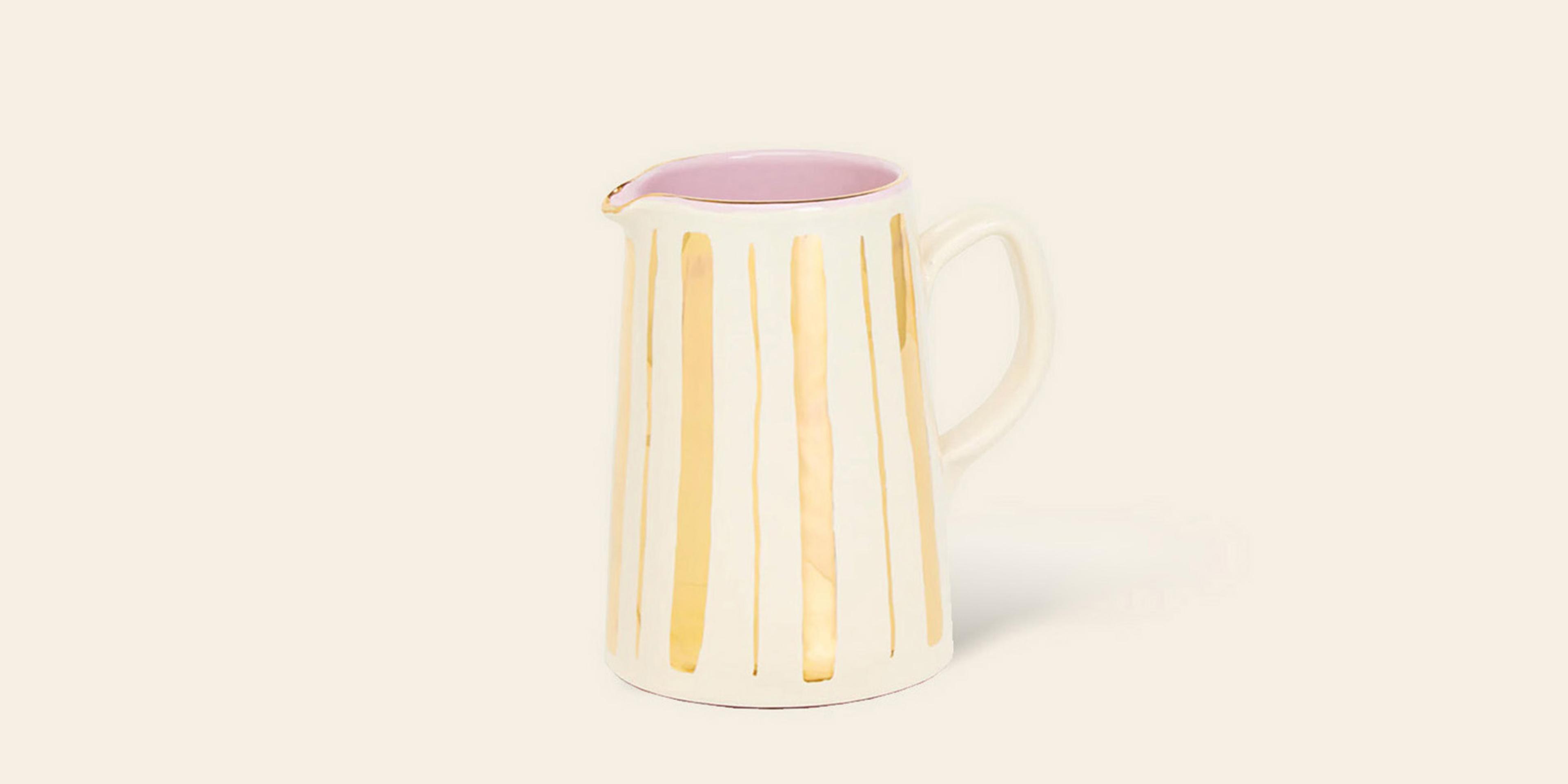 A gold and cream tall jug with handle and pink interior glaze