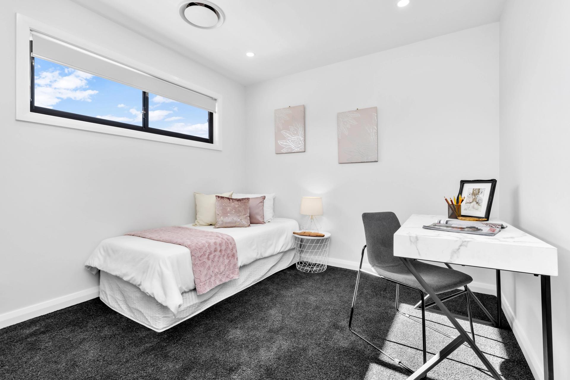 small kids bedroom with single bed, table, high window, white walls and grey carpet, built by Balwin Homes