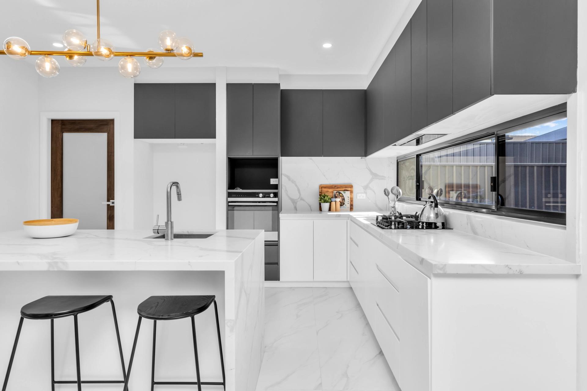 side view of modern kitchen showing stovetop, latest appliances, and waterfall island benchtop, built by Balwin Homes