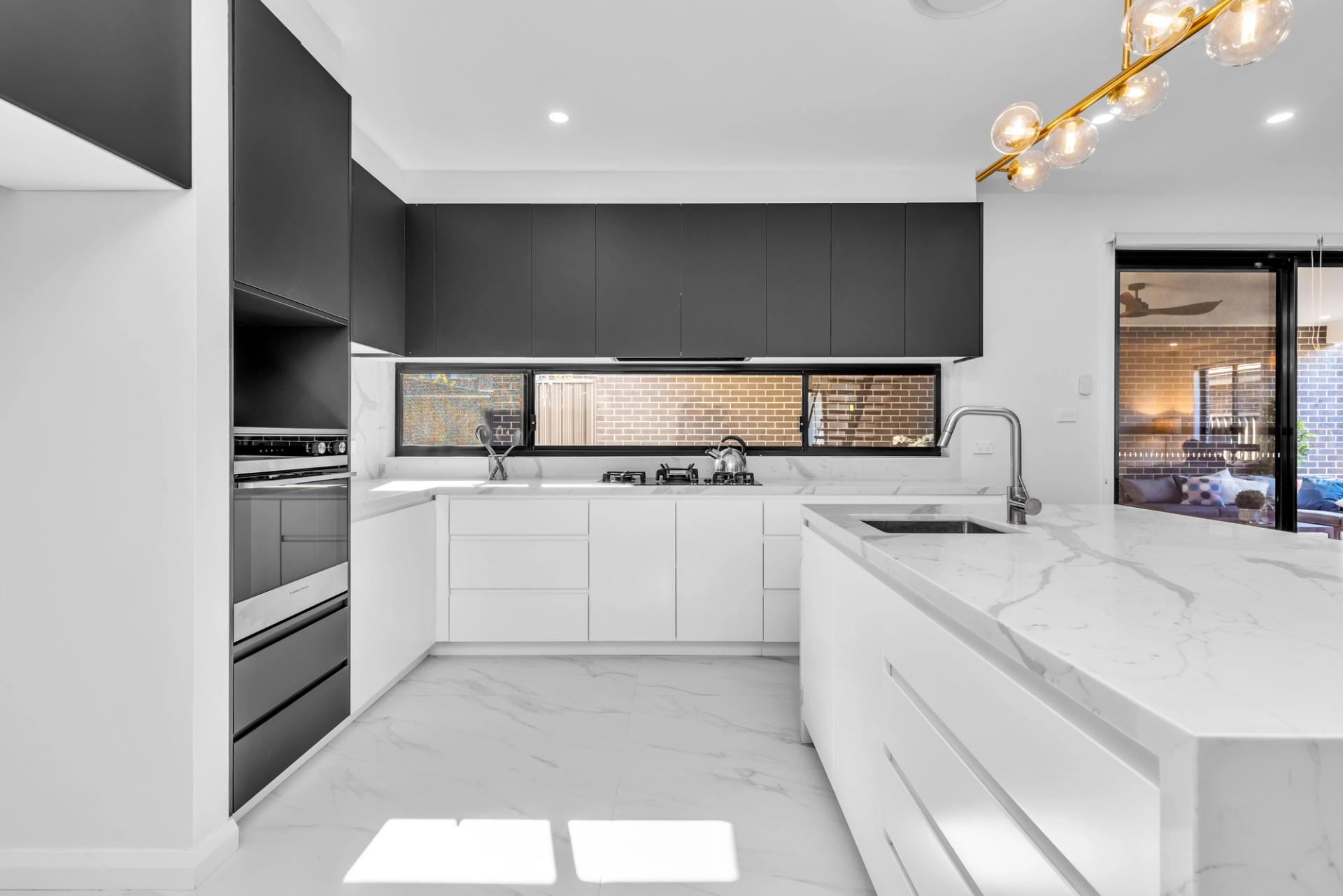 modern kitchen with waterfall island, overhead cupboards, lights, and latest appliances, built by Balwin Homes