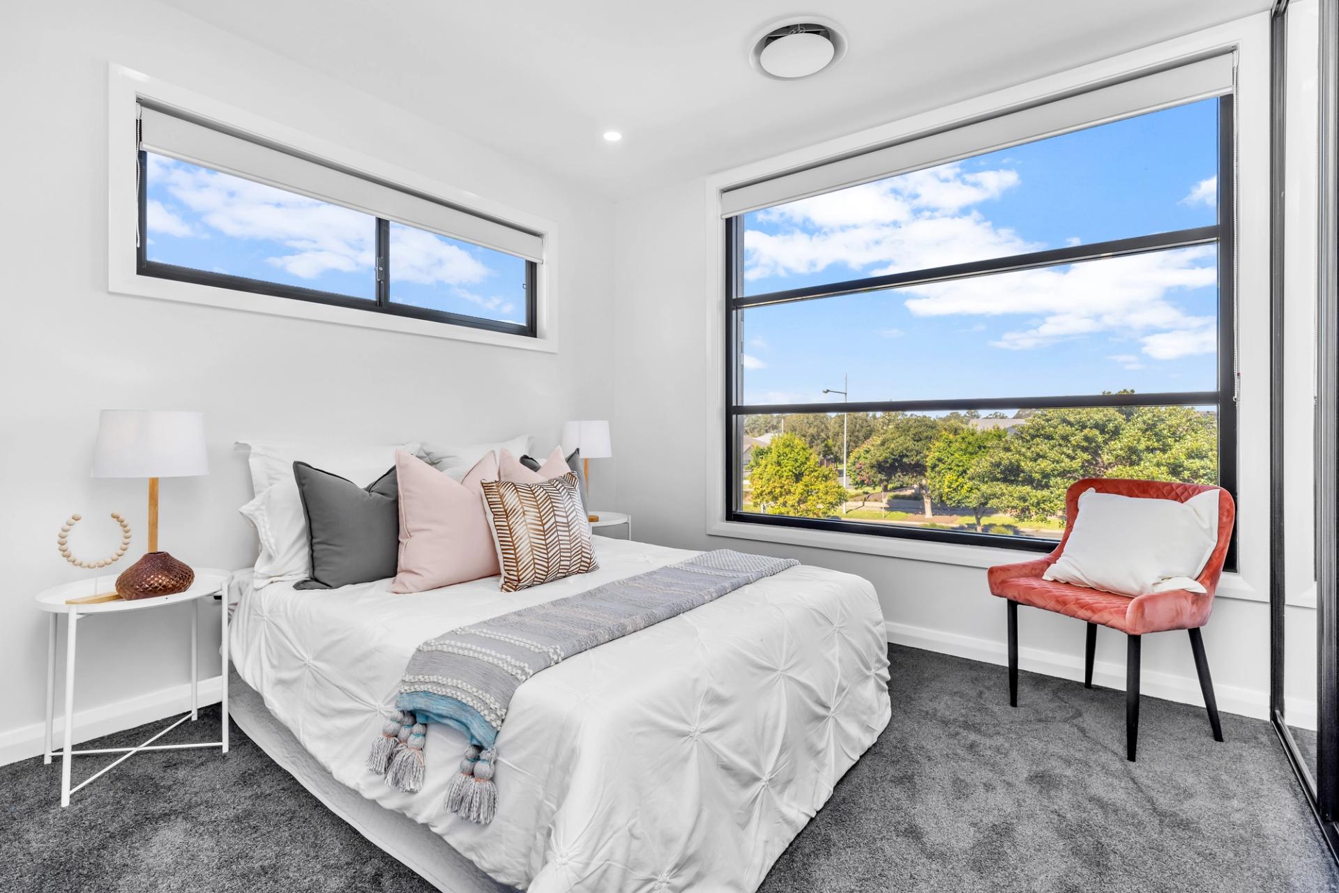 modern bedroom with white walls, grey carpet and large window overlooking trees and sky, built by Balwin Homes