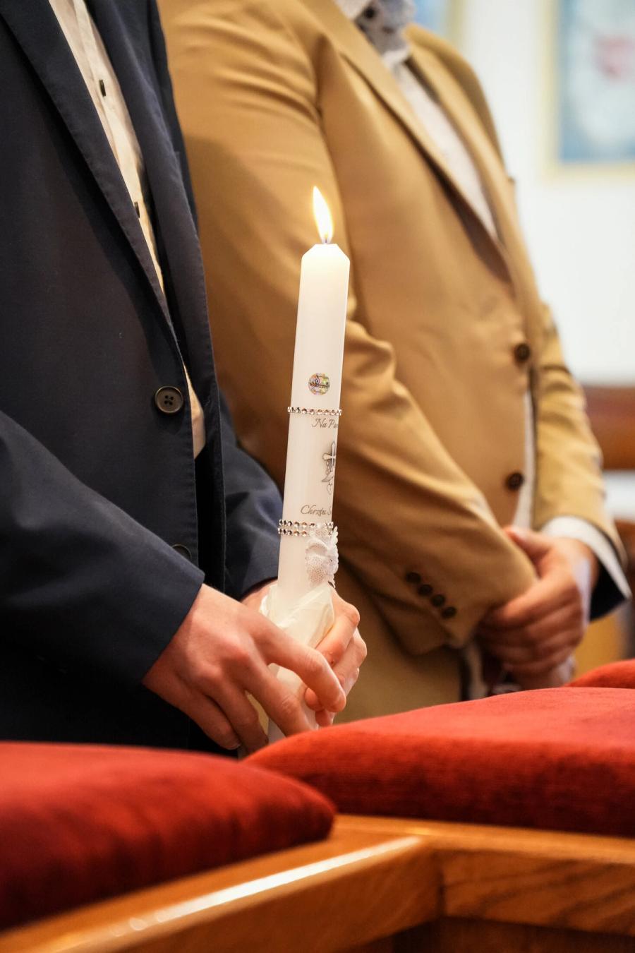 Detal świecy trzymanej podczas ceremonii chrztu - Janiczek Foto