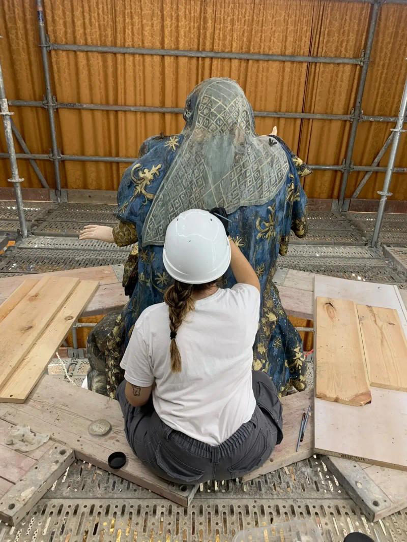 Andrea trabajando con casco sobre el andamio del retablo