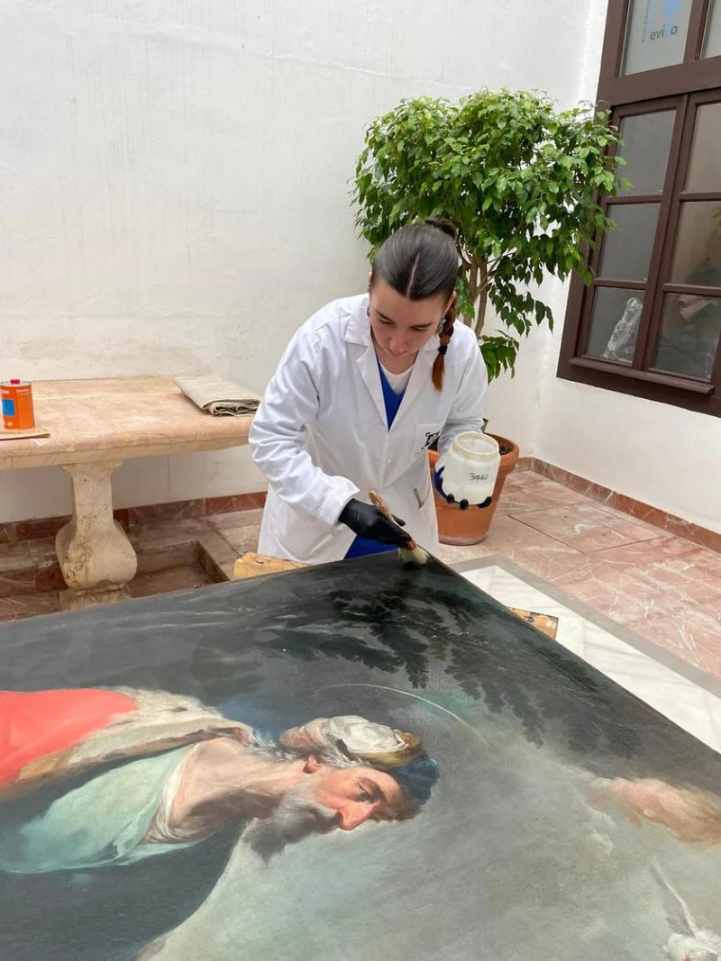 Andrea barnizando la pintura a brocha tras la limpieza del barniz
