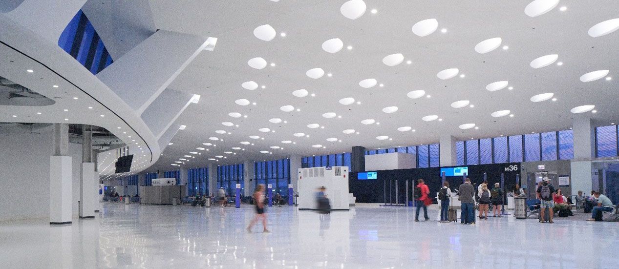 Travelers crossing a bright terminal at Chicago O'Hare beneath a curved white ceiling of USG panels.