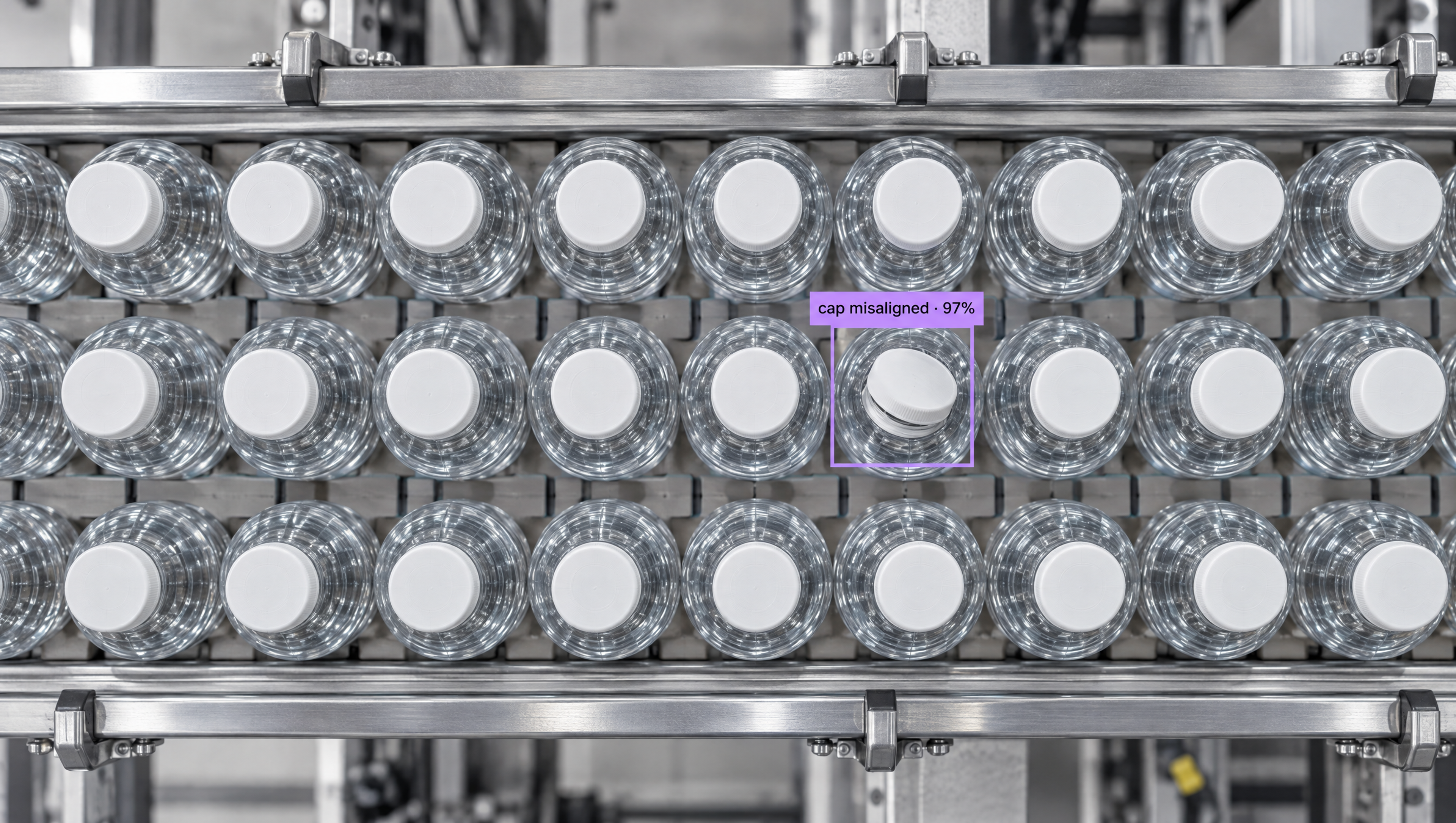 Overhead view of water bottles on a conveyor belt, with one bottle cap highlighted by AI as "cap misaligned."