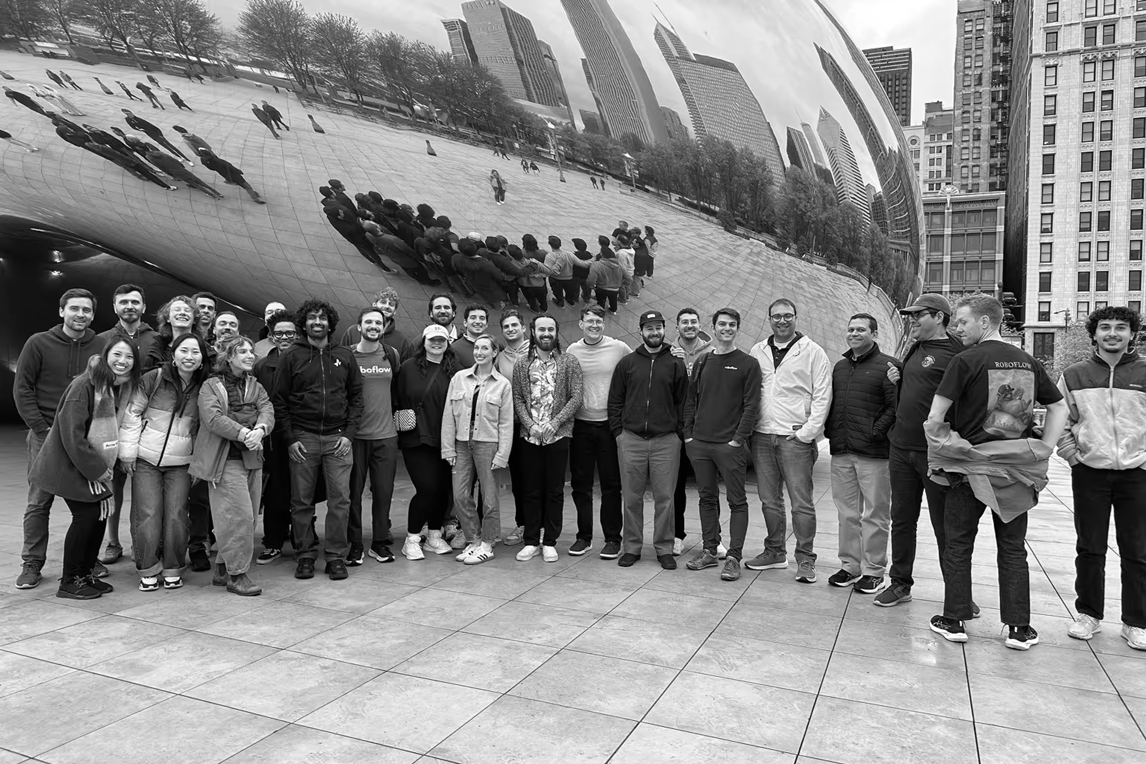 A group of people posing in front of Chicago's reflective Cloud Gate sculpture.