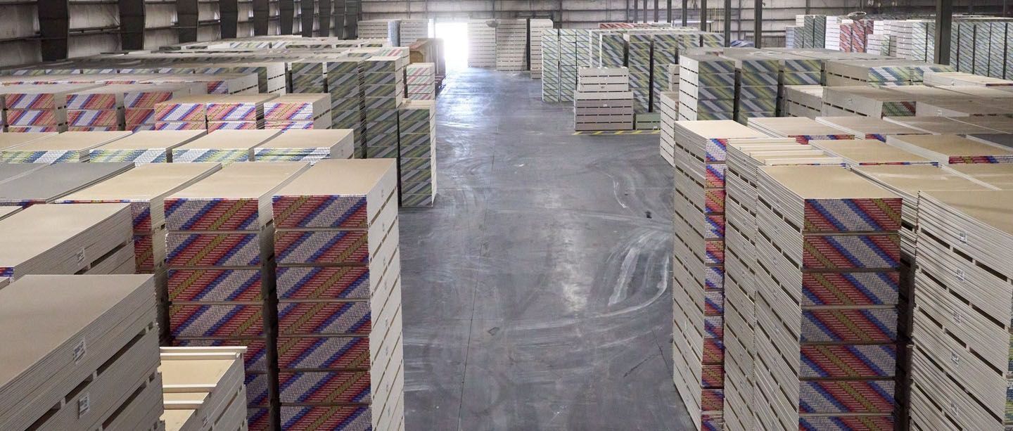 Stacks of banded USG drywall panels filling a warehouse aisle.