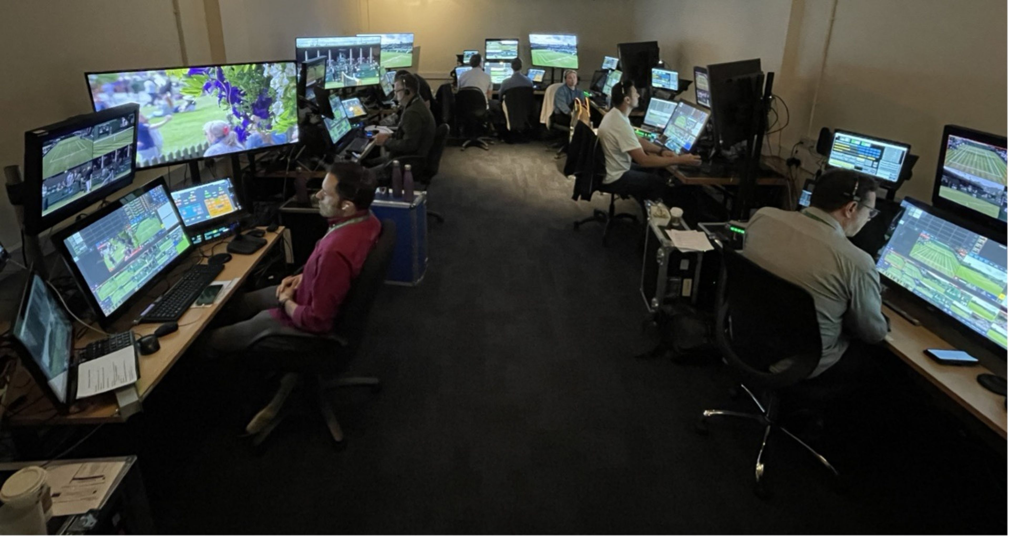 Operators at banks of monitors in a darkened room, each screen carrying a different camera angle of a tennis match.