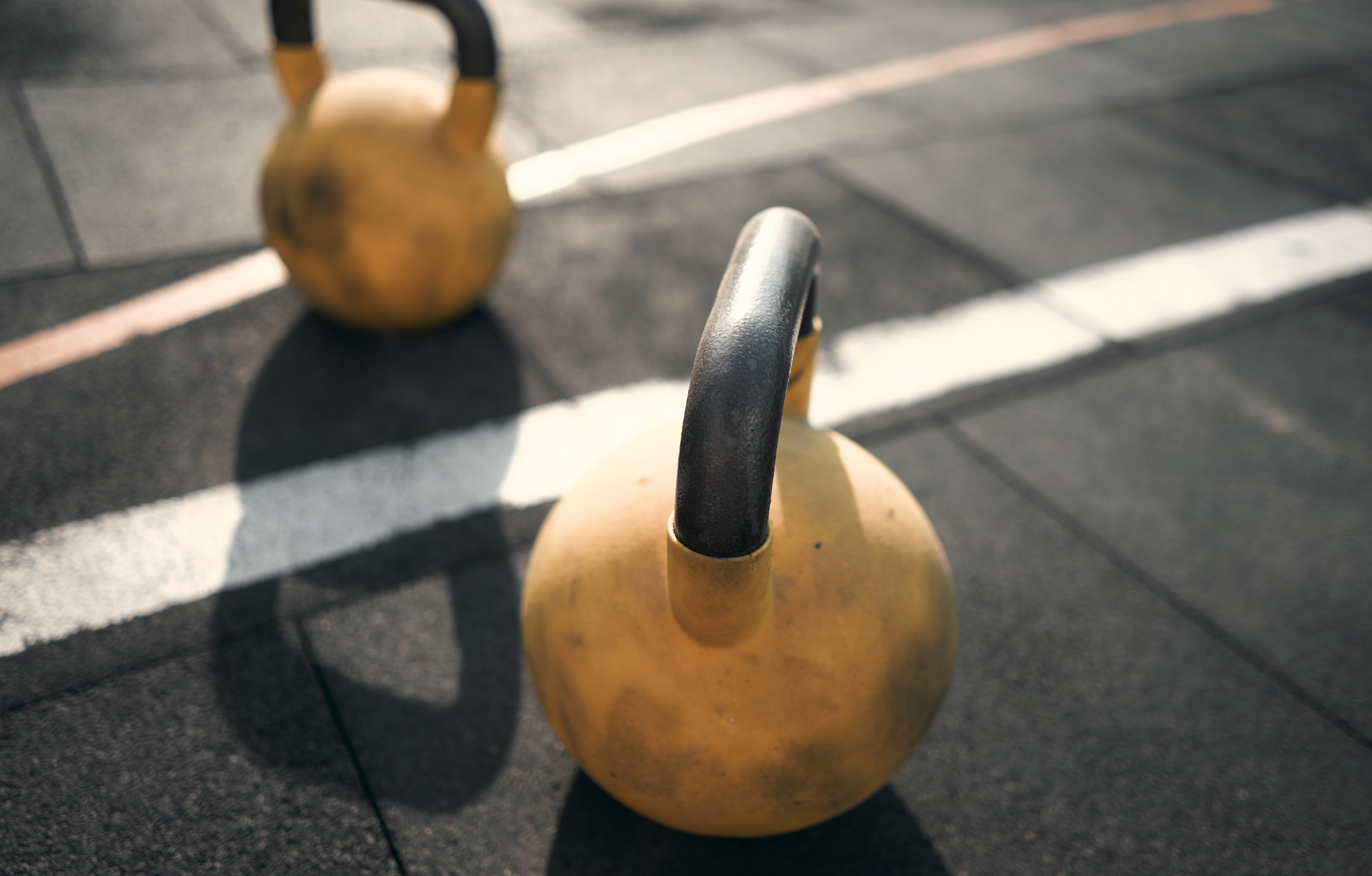 Two yellow dumbbells positioned on the floor in the air gym