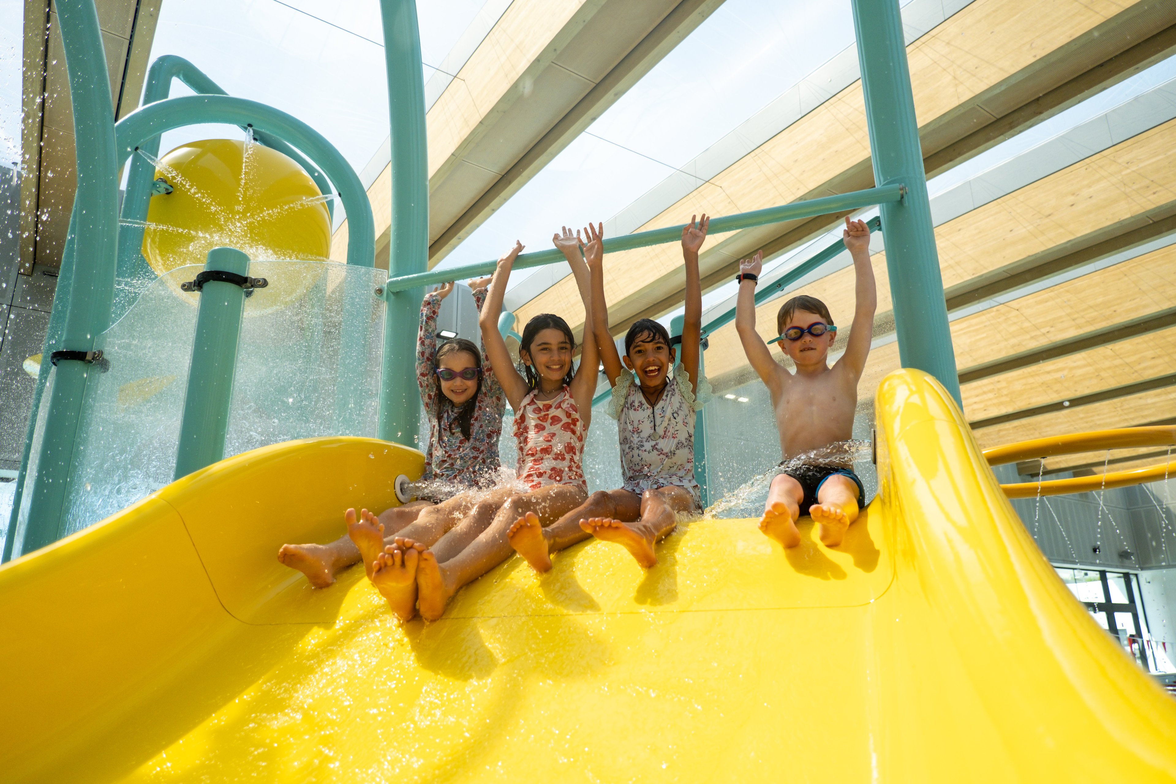 A group of children sliding down the yellow waterslide at Gunyama Park