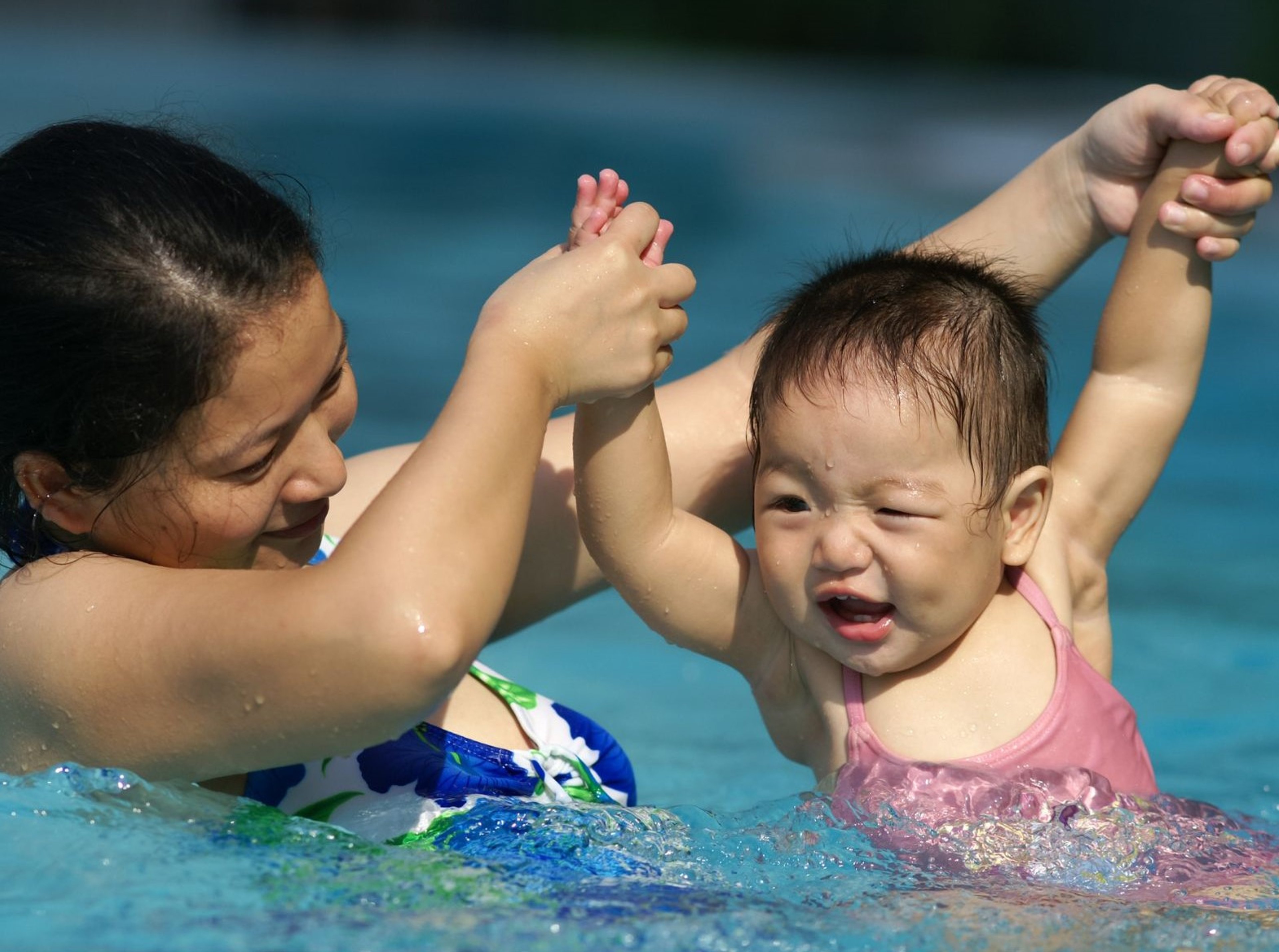 Woman helping toddler in the pool during a swimming lesson 