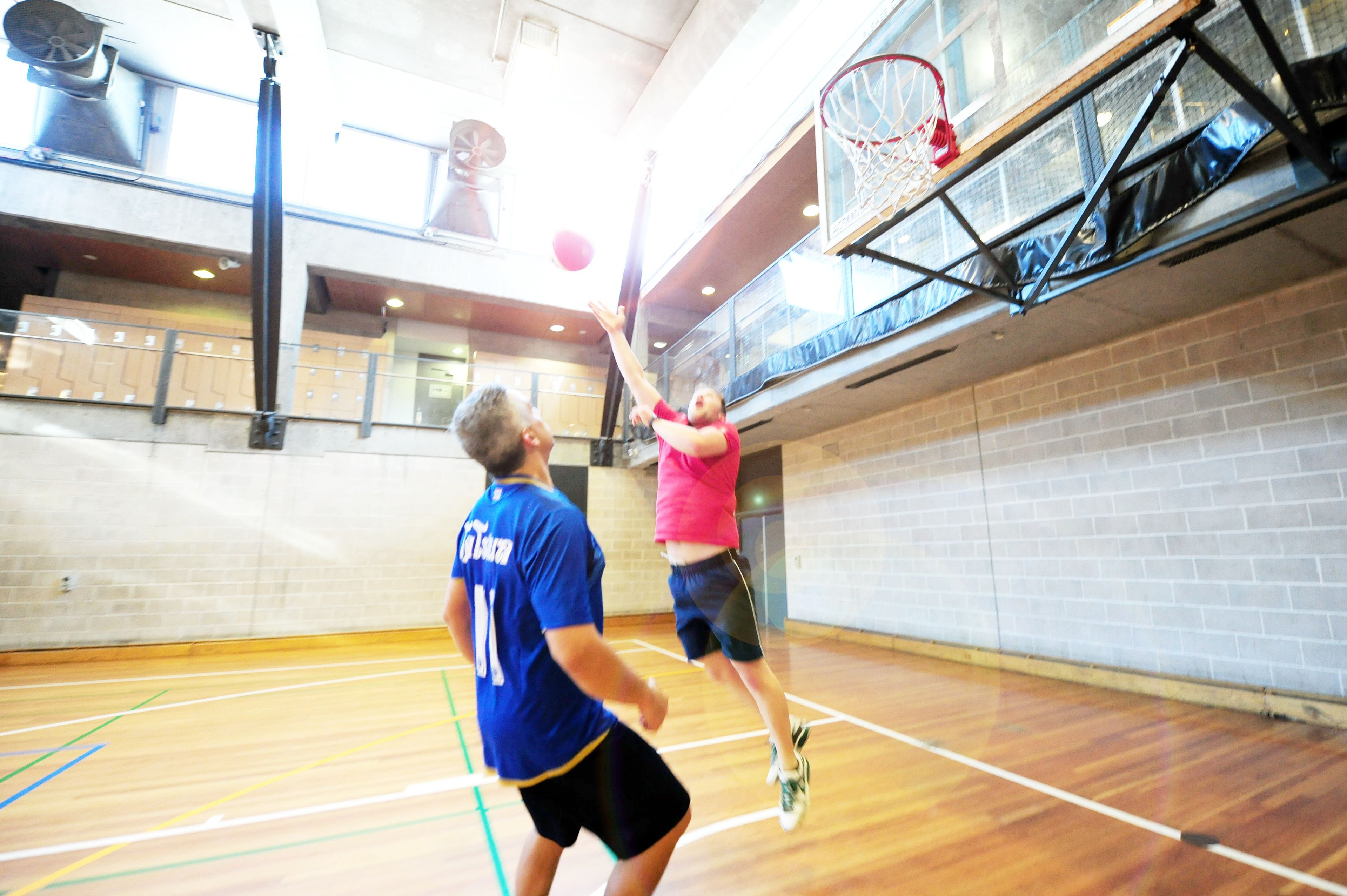 Two males playing basketball on the sports court at Cook + Phillip Park Pool