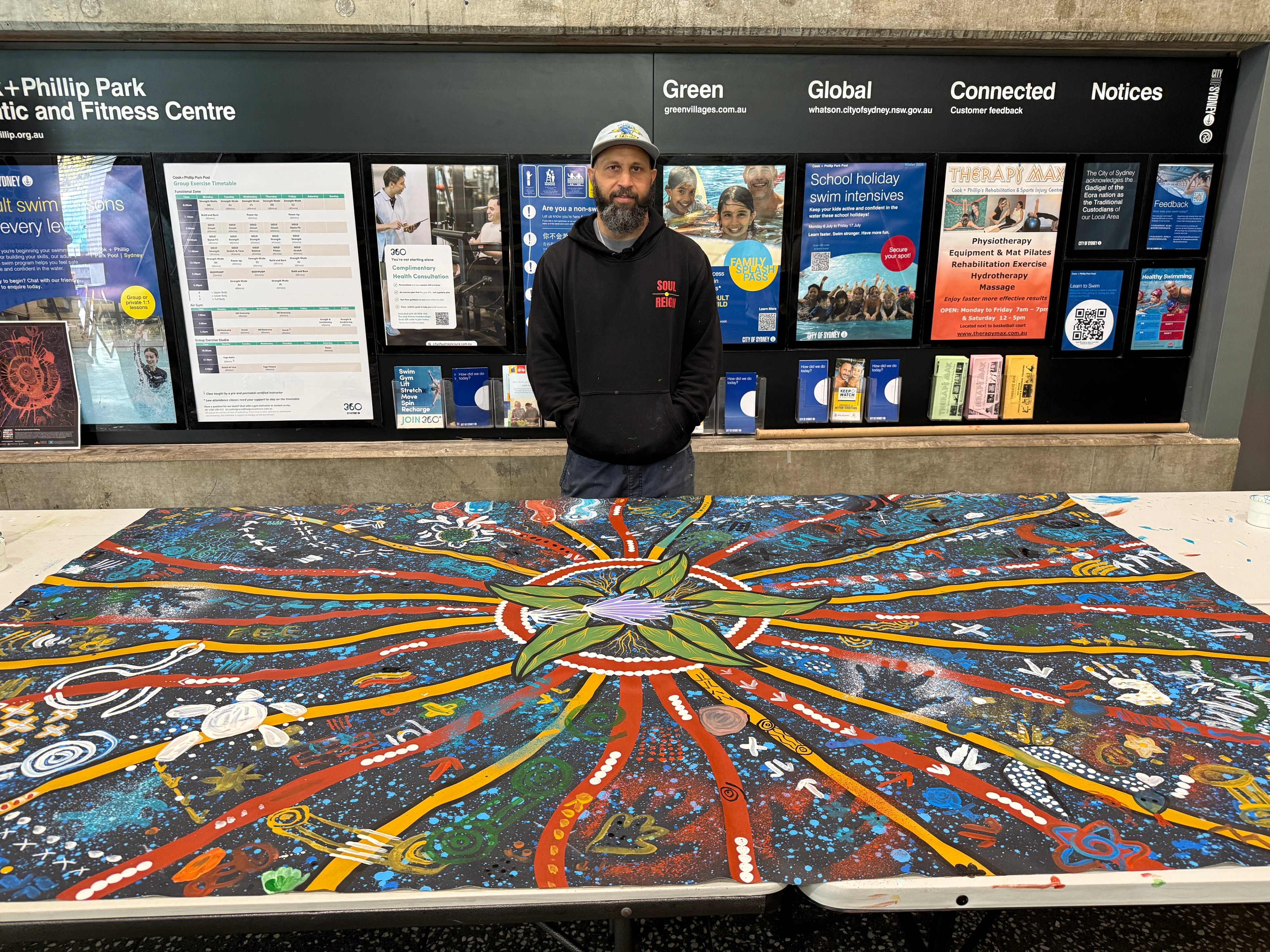 Lyle, founding artist of Soul Reign, with the finished collaborative artwork celebrating 50 Years of Deadly