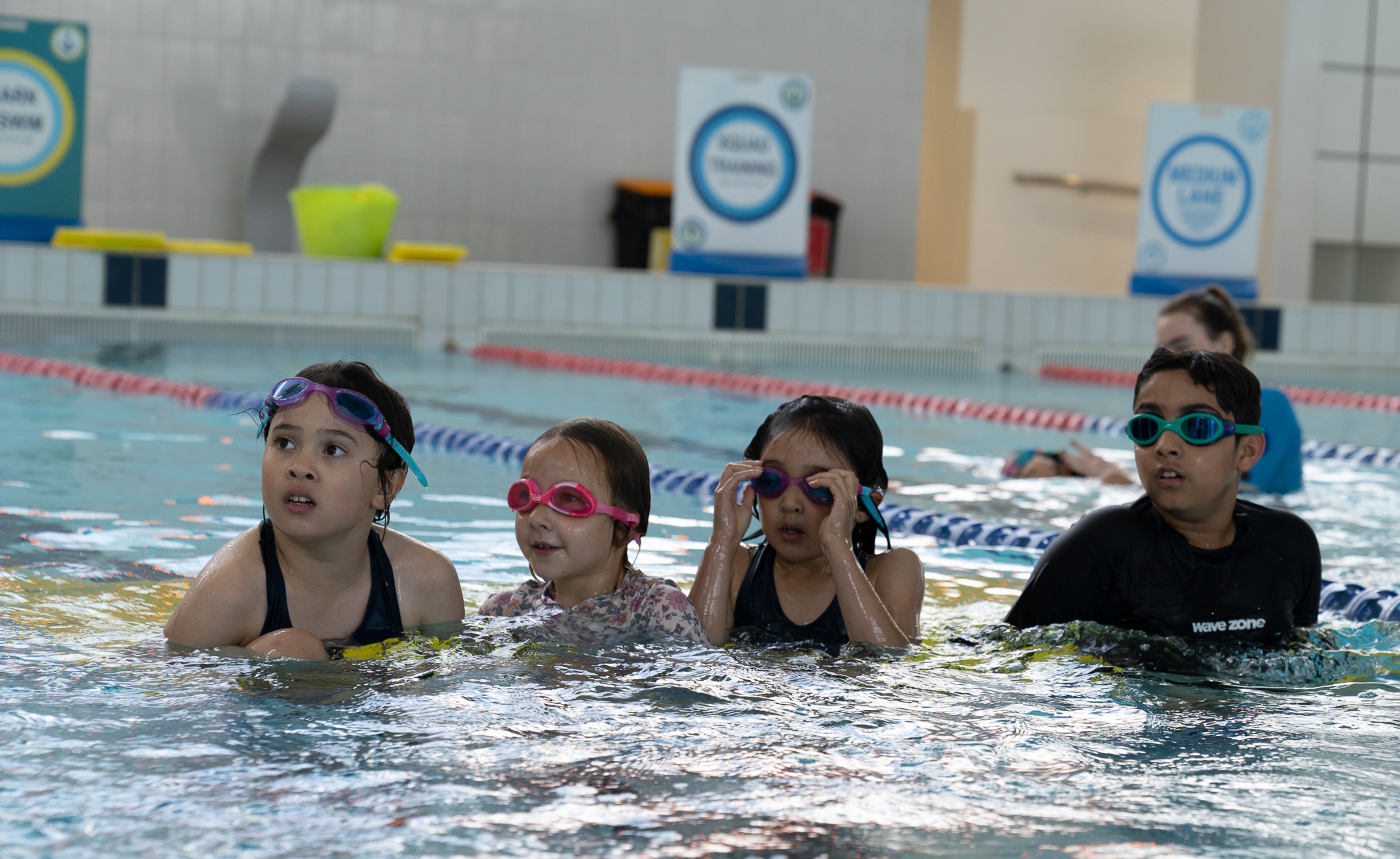 Four children wearing goggles in the pool during a swim lesson at Ian Thorpe Aquatic Centre