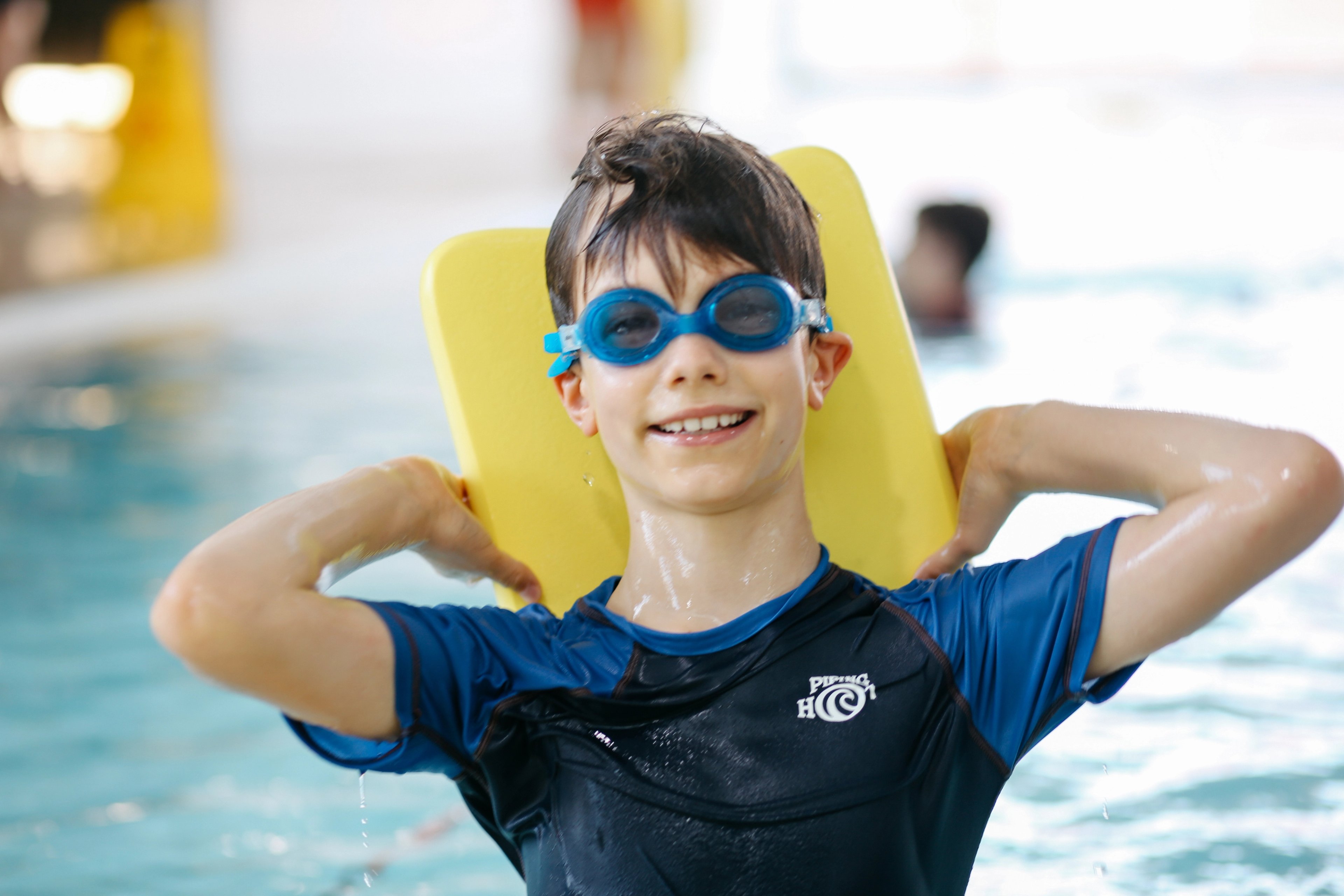 Young boy wearing goggles and holding a yellow kickboard while in the pool at Ian Thorpe Aquatic Centre