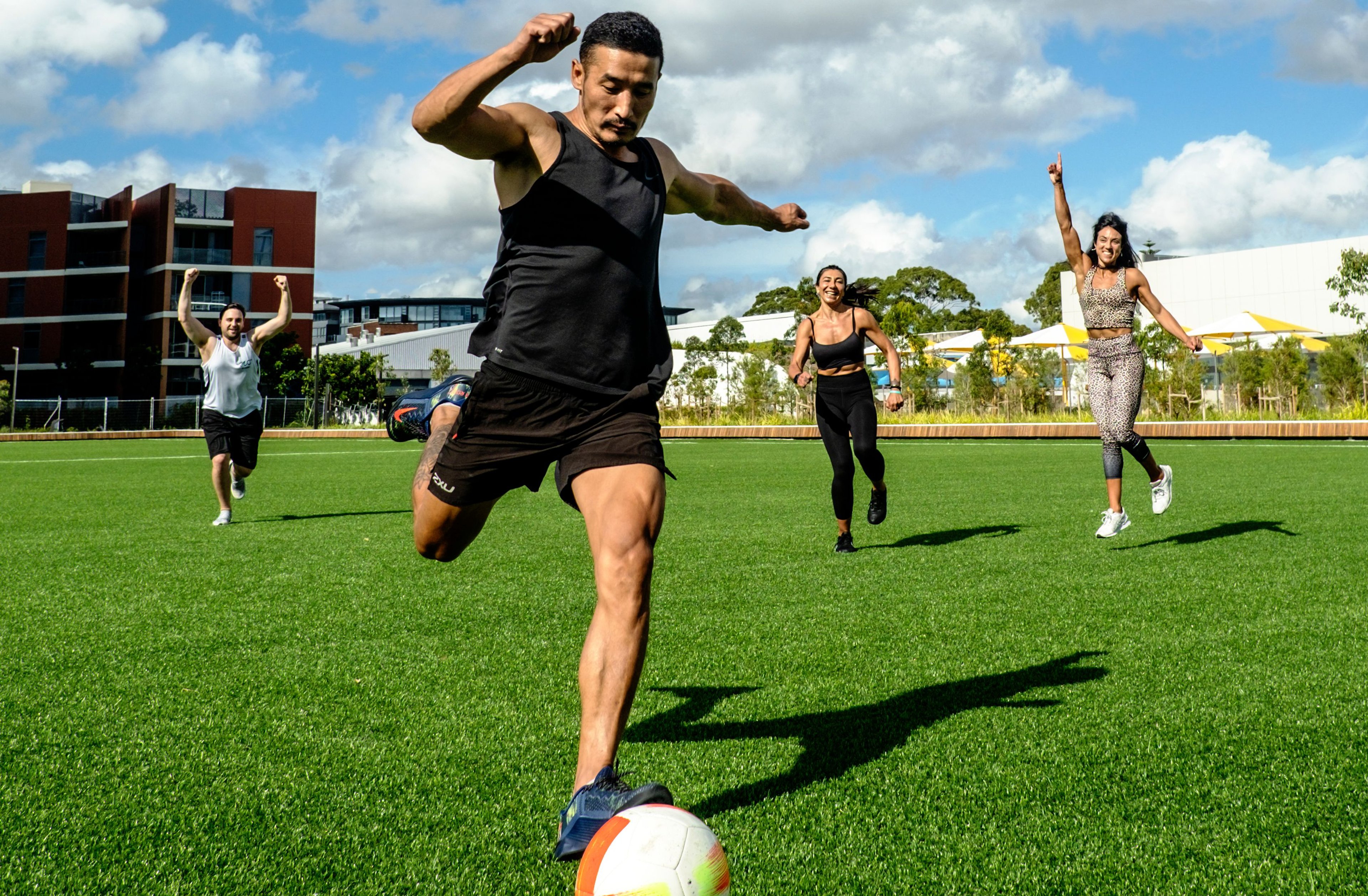 Group of soccer players kick the ball on the Gunyama Park outdoor sports field