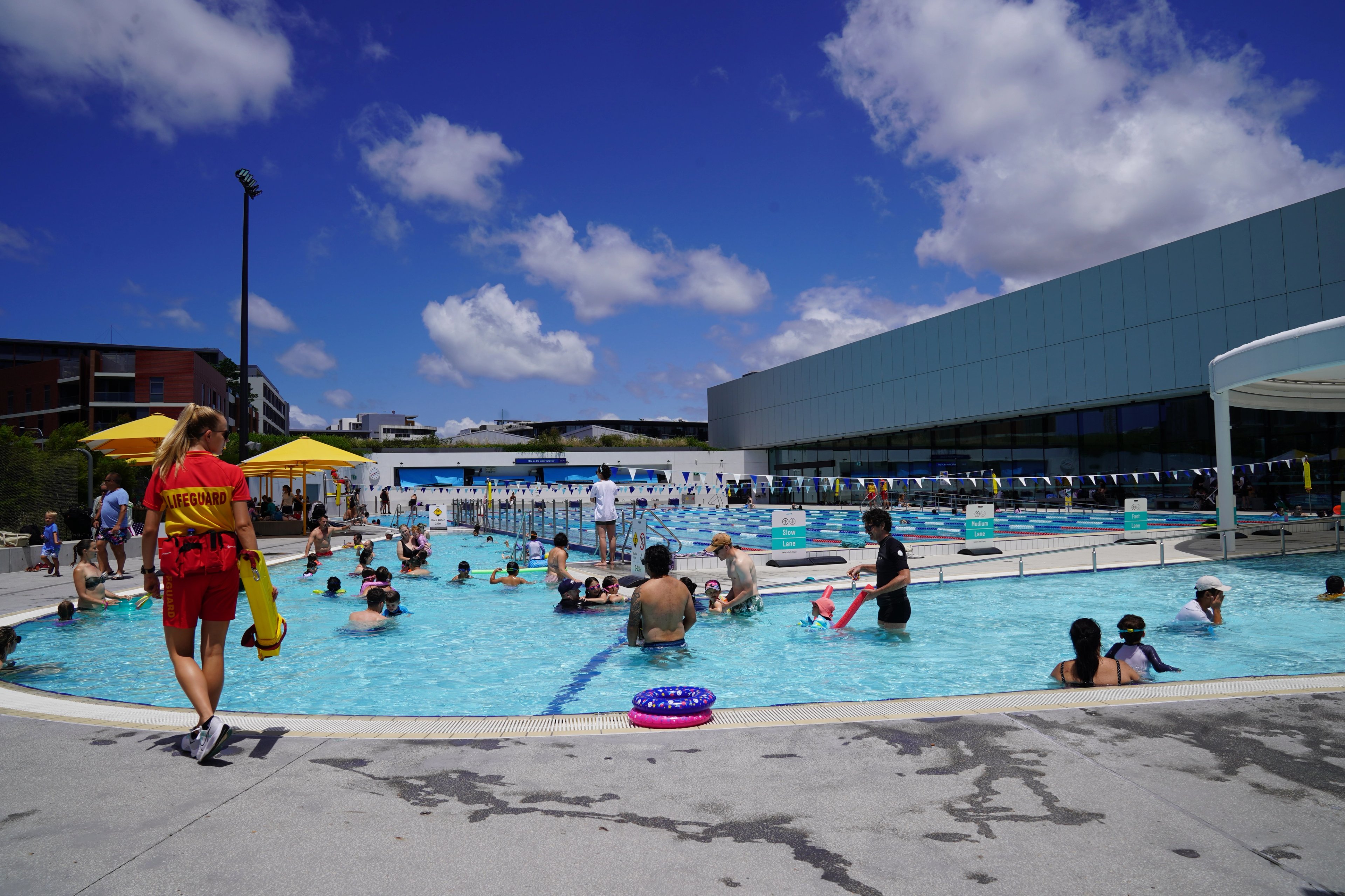 Patrons in the outdoor leisure and 50m pool, with a lifeguard standing by, at Gunyama Park