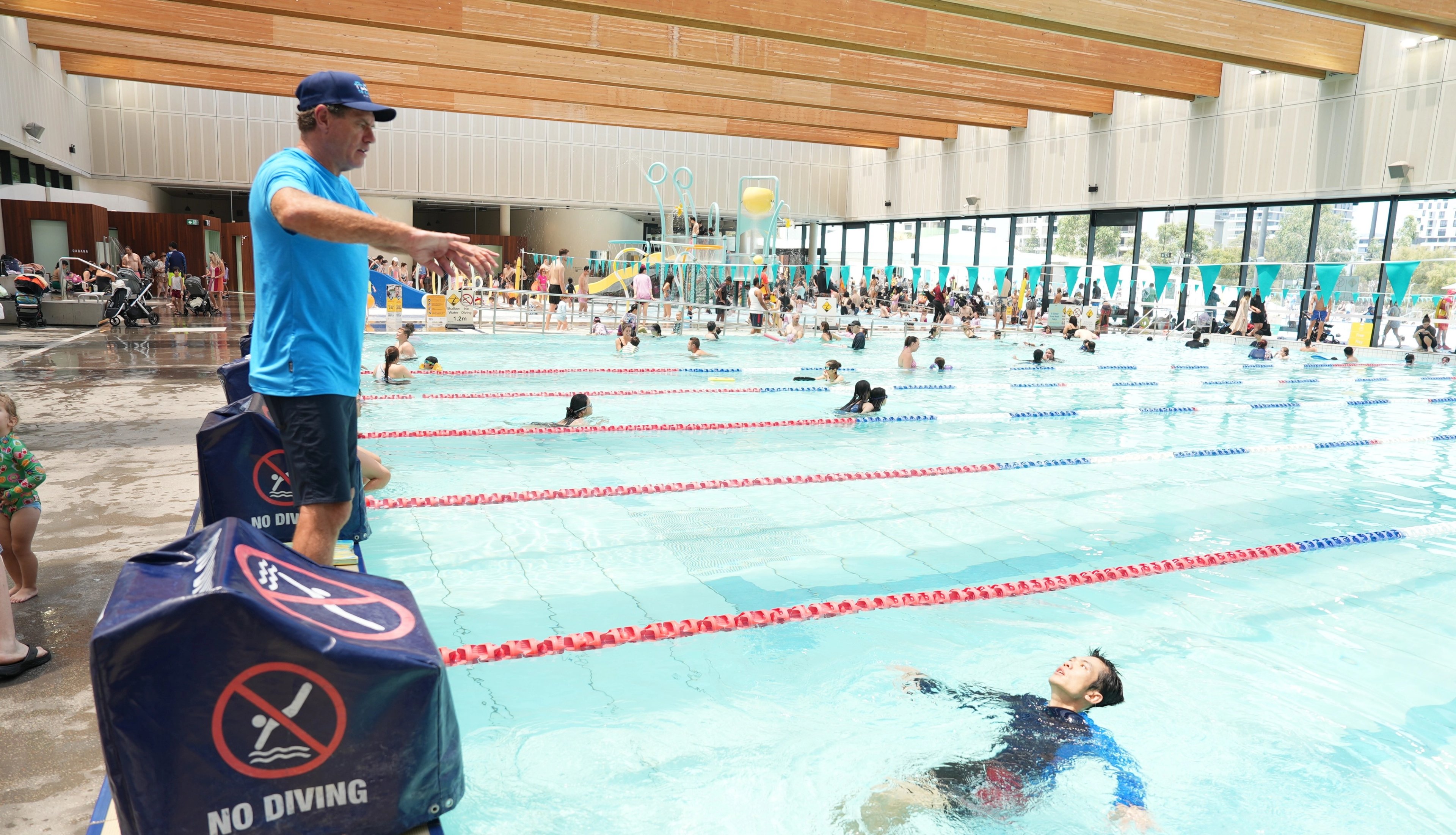 Lifeguard Hoppo assisting a swimmer with a Float to Survive demonstration at Gunyama Park indoor pool