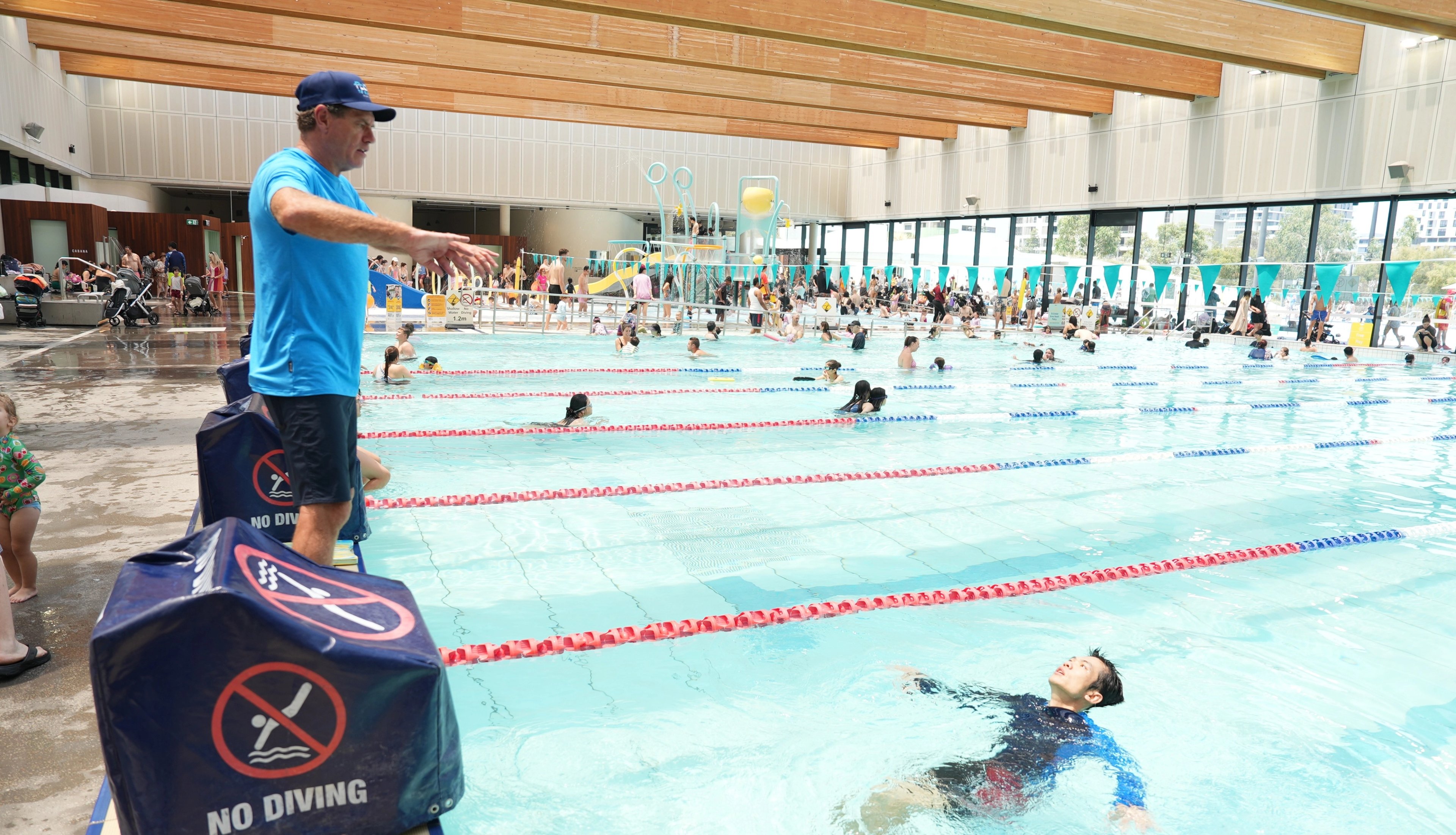 Lifeguard Hoppo assisting a swimmer with a Float to Survive demonstration at Gunyama Park indoor pool 