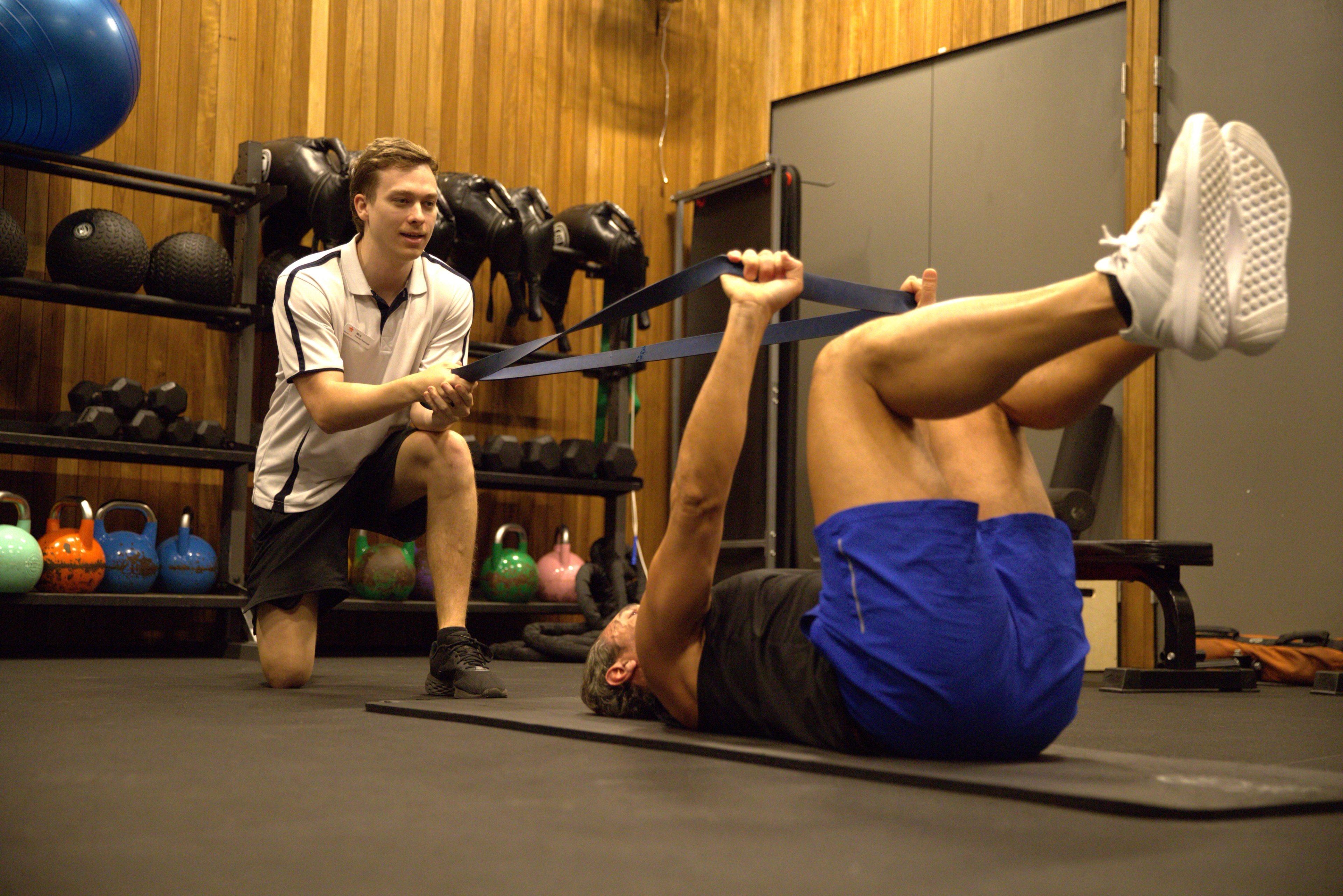 Exercise physiologist Nick guiding a client to stretch using a resistance band