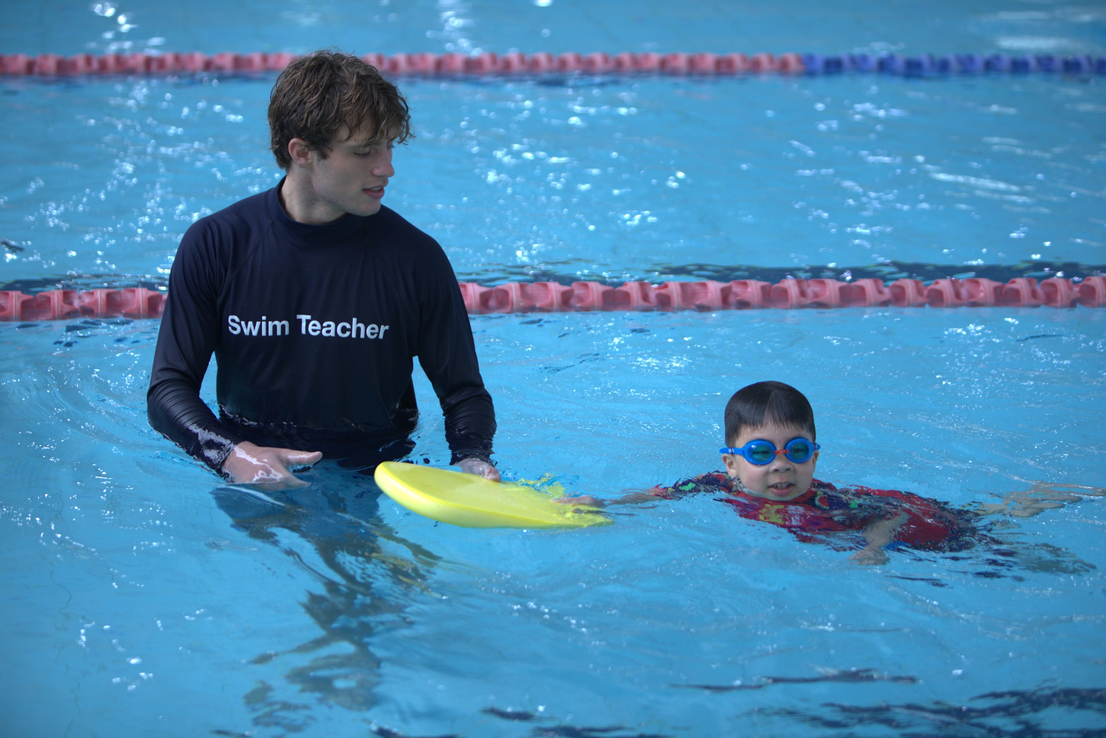 Young boy with a swim teacher during a learn to swim lesson 