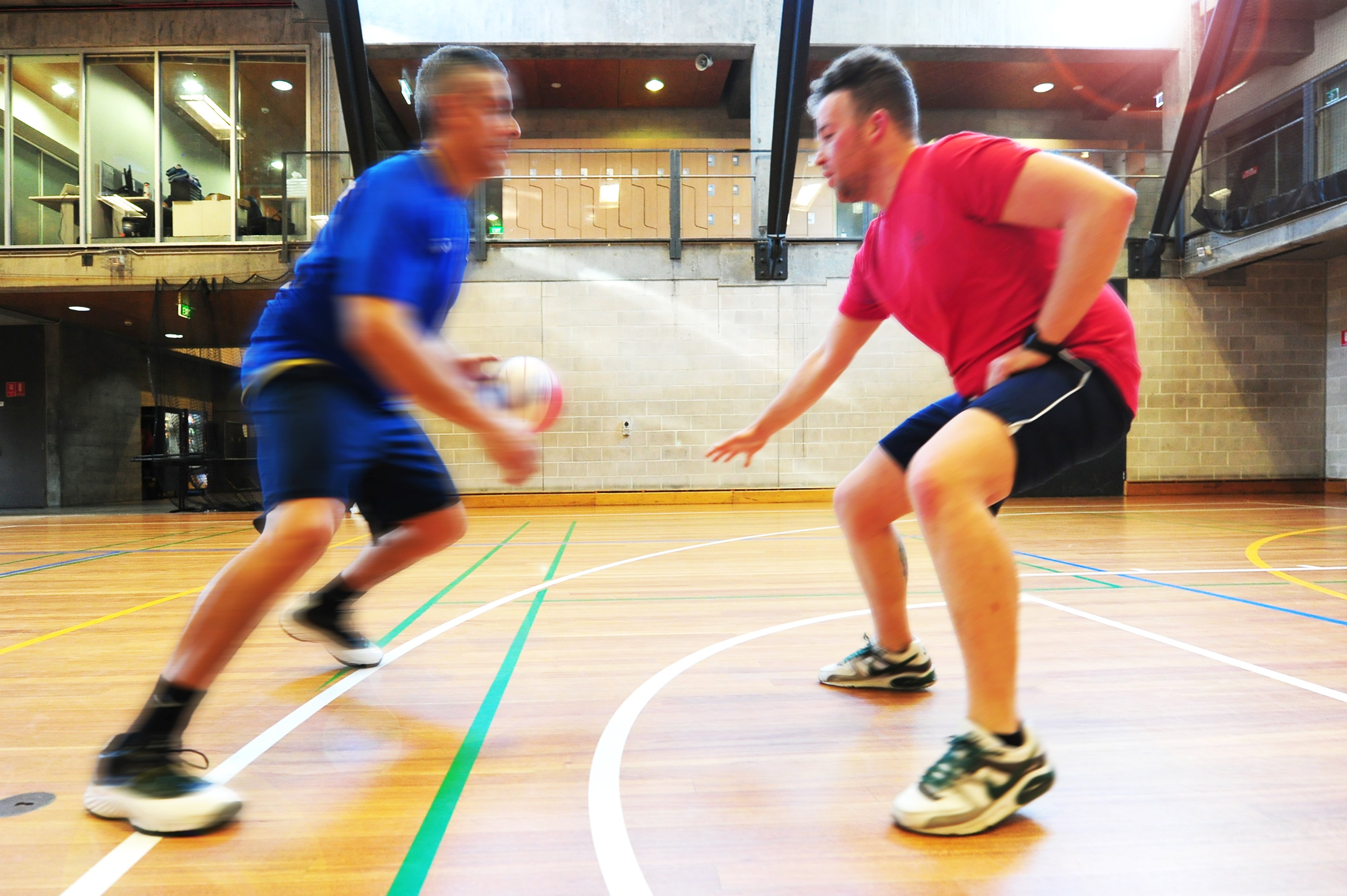 Two men playing basketball on the sports court at Cook + Phillip Park Pool