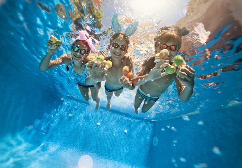 Three children swimming underwater wearing bunny ears