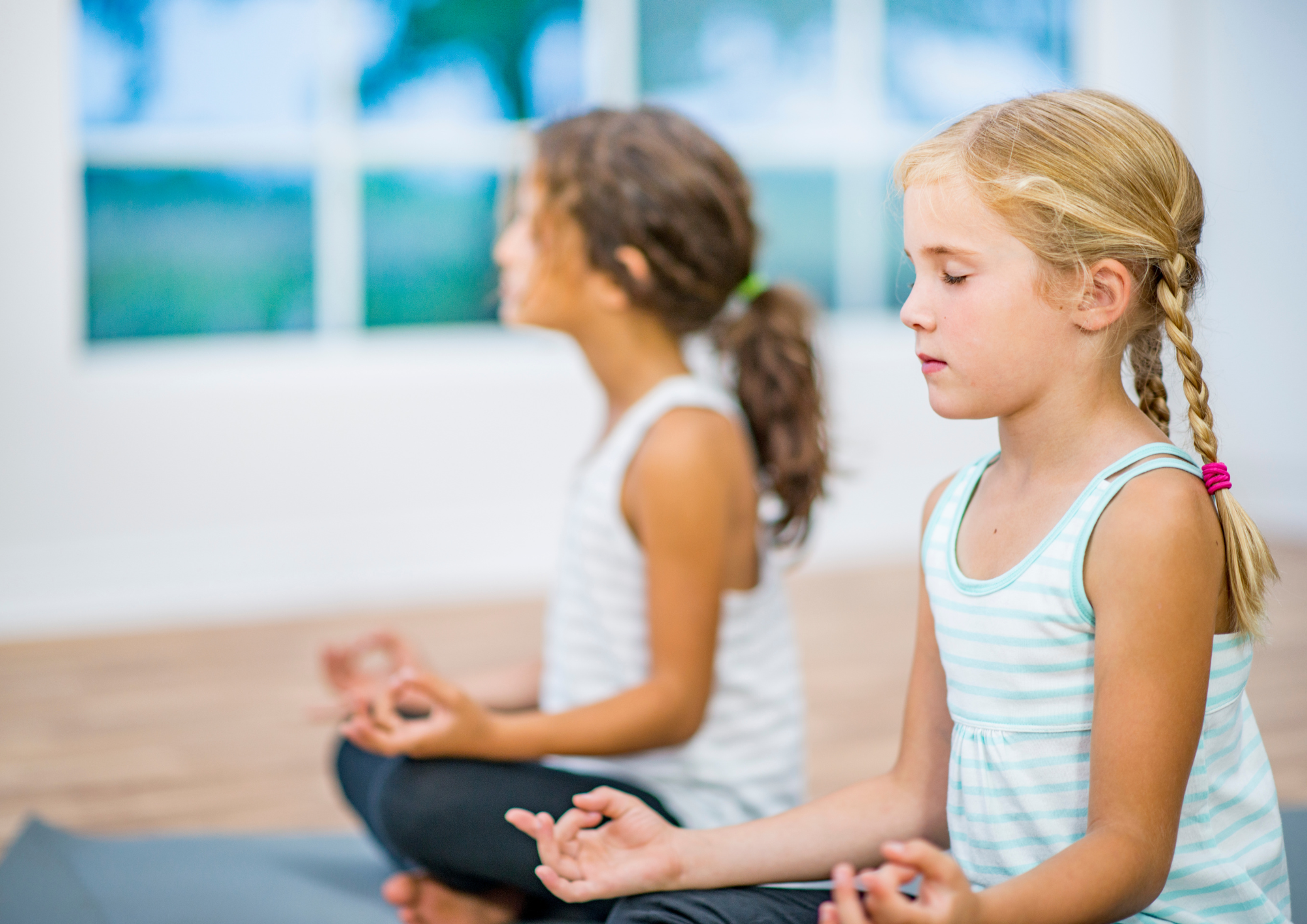 Two kids sitting in a yoga pose during a kids yoga class 