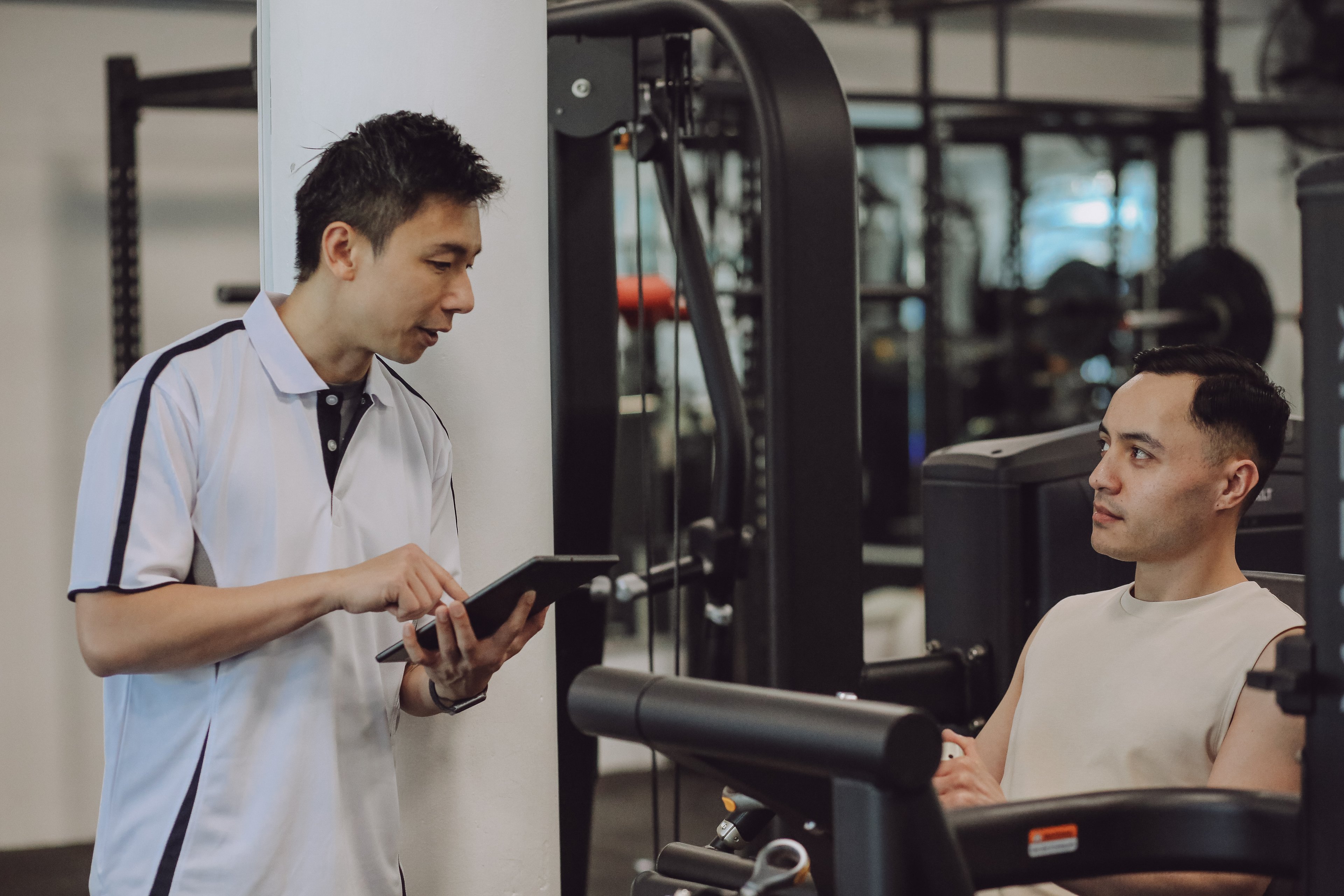 Personal Trainer talking to a male participant using a machine in the gym at Victoria Park Pool 