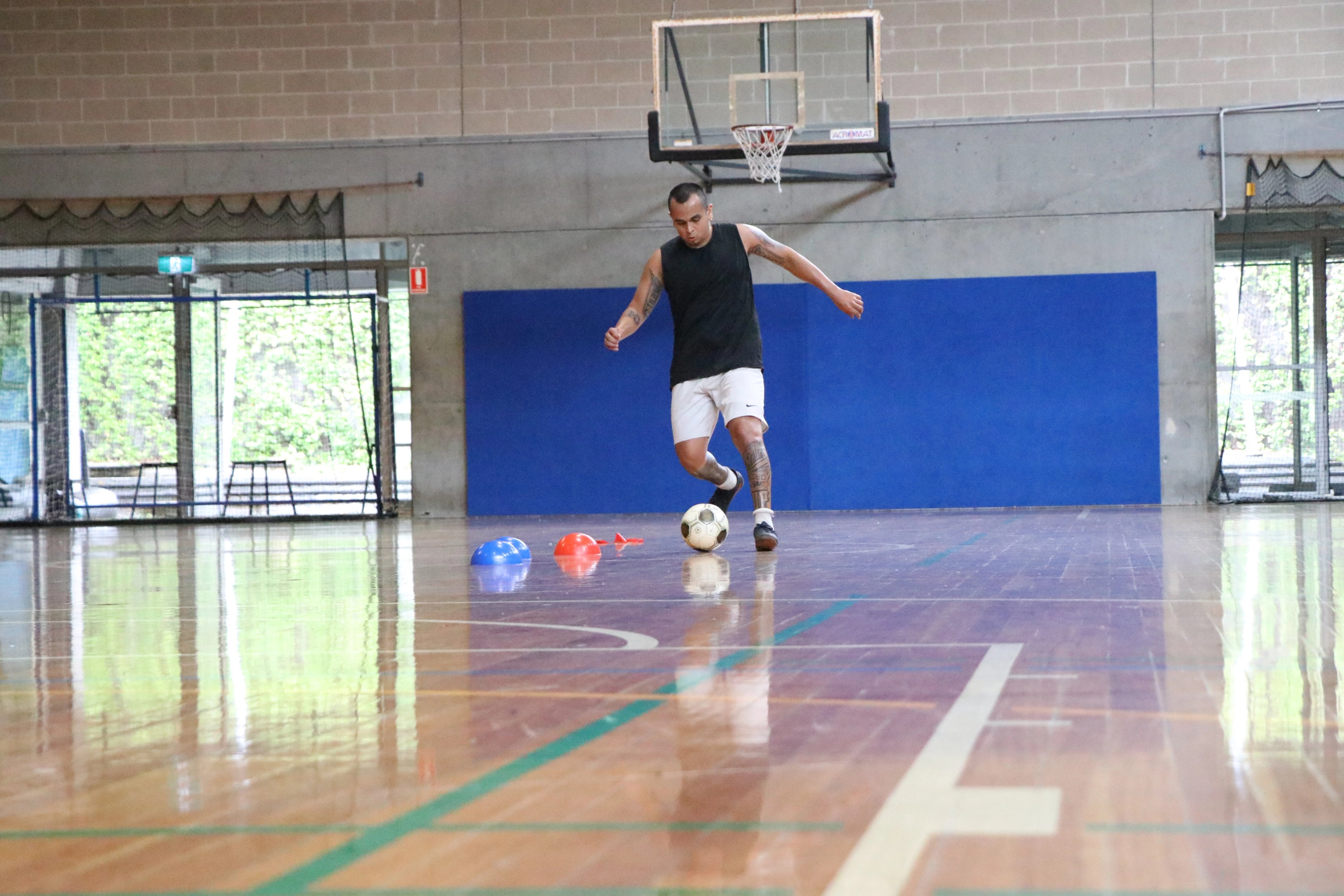 Man playing a game of futsal on the indoor sports court at Cook + Phillip Park Pool