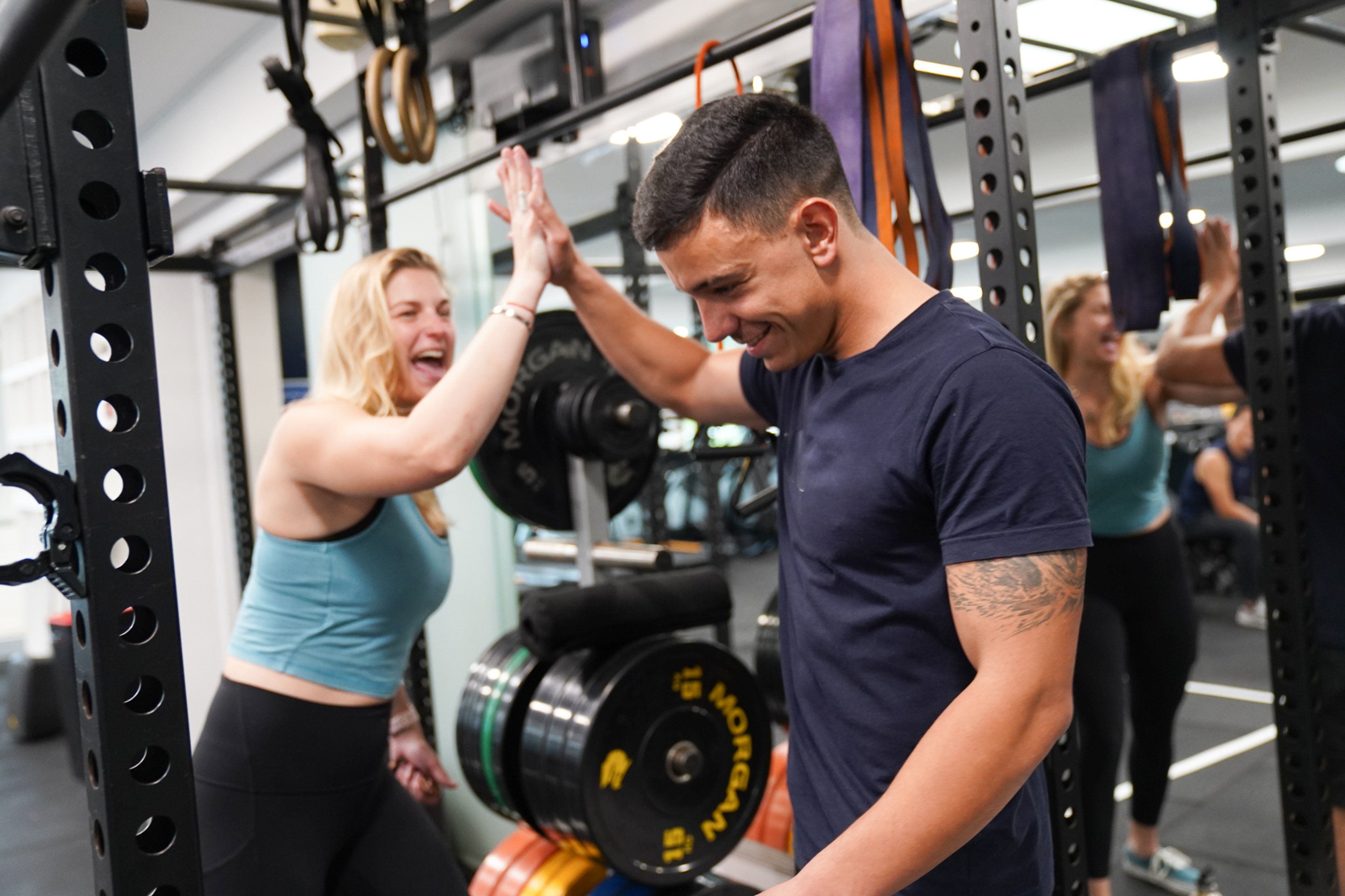 A man and a woman high-fiving one another in the gym at Victoria Park Pool