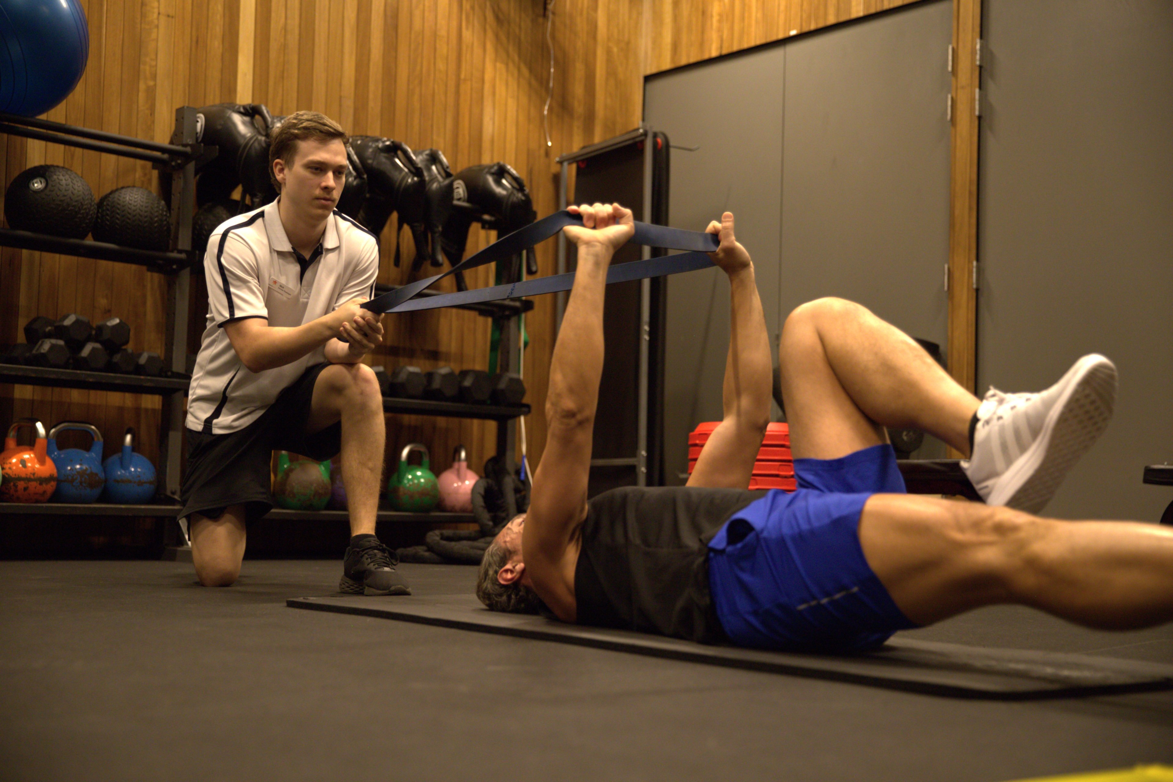 Nick guides a client through resistance band stretches during an Exercise Physiology session